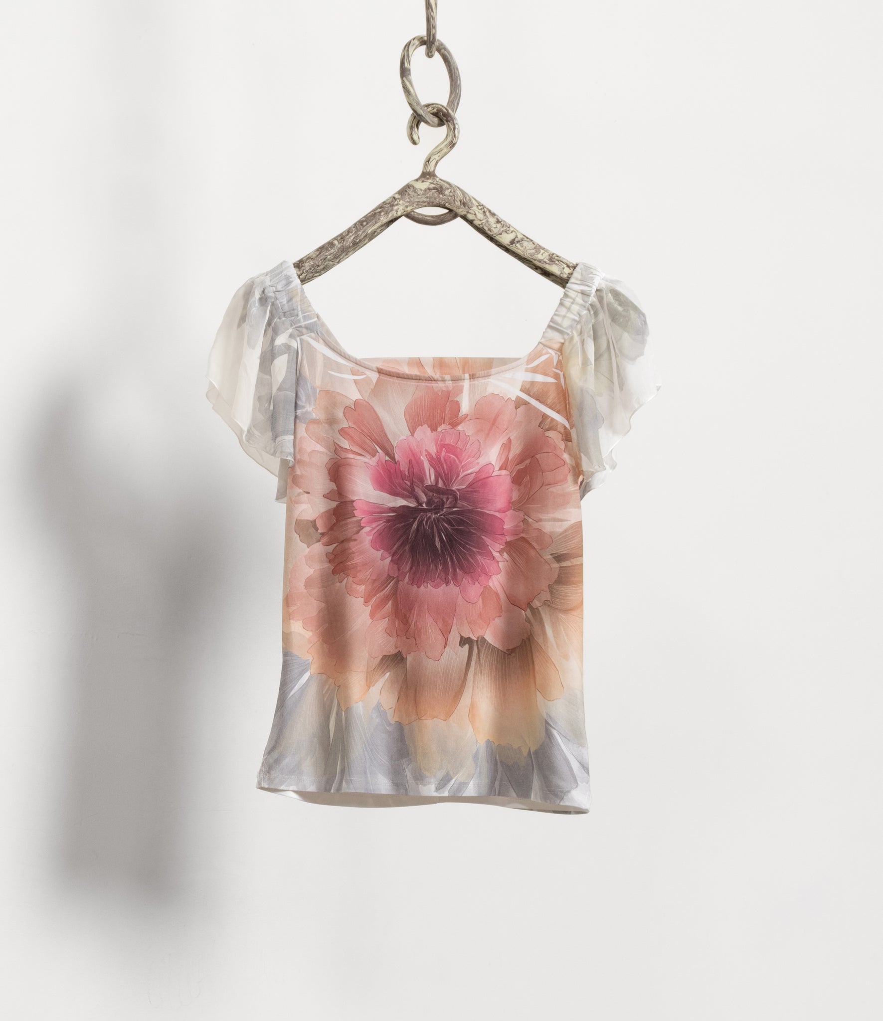 Floral top hanging on a hook against a white background
