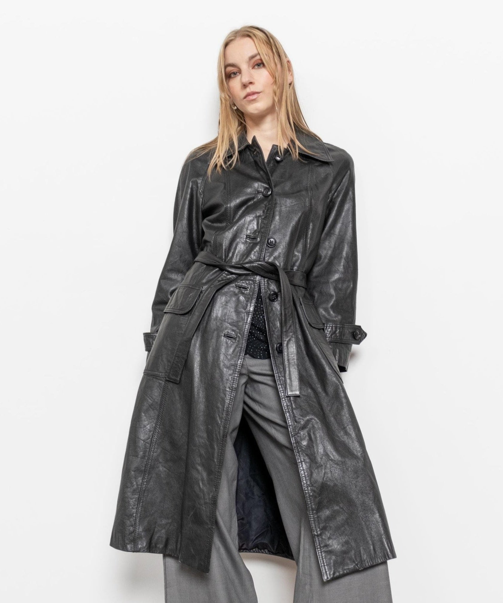 Woman wearing a long black leather coat on a white background