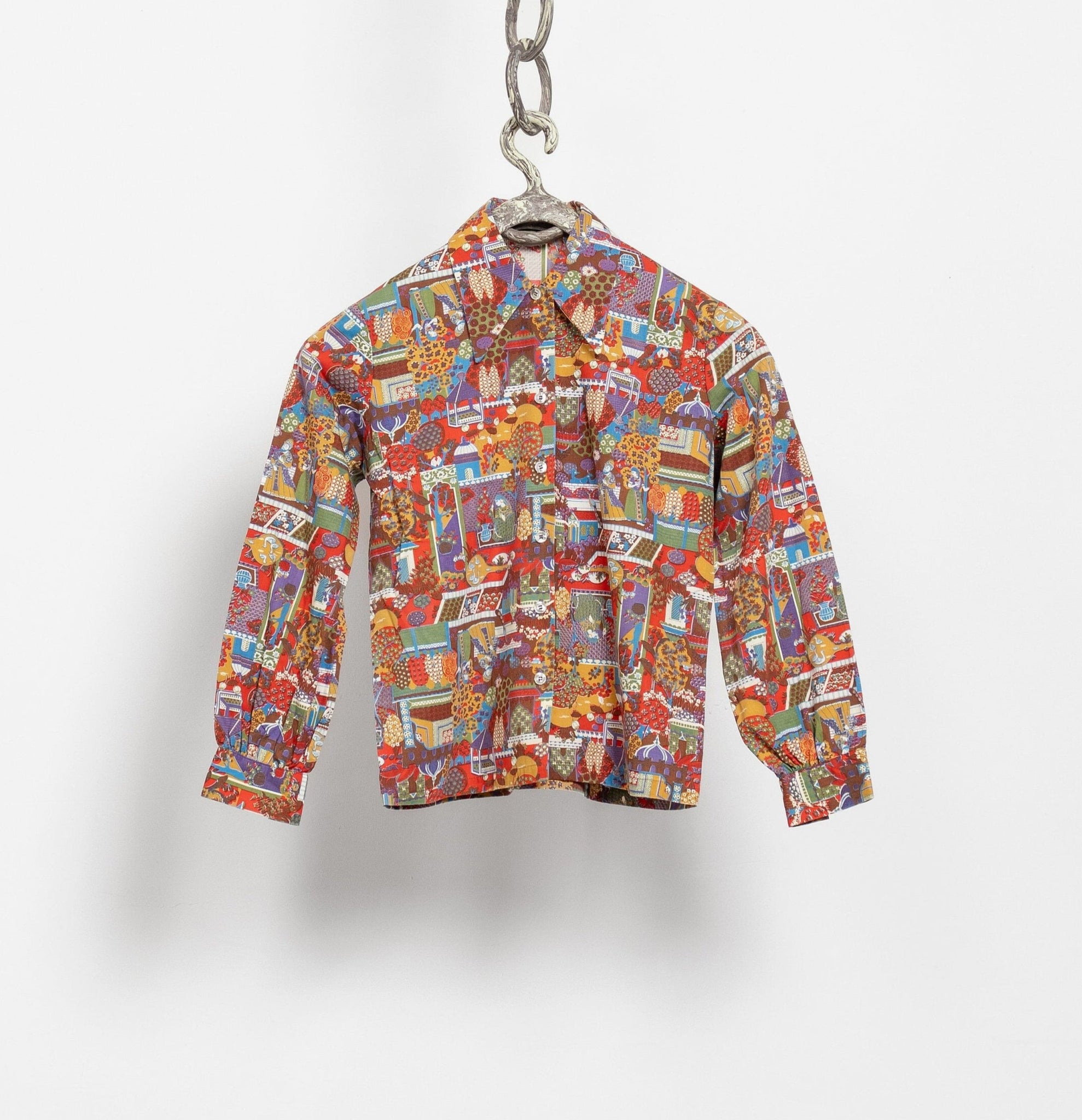 Colorful patterned shirt hanging on a hook against a white background