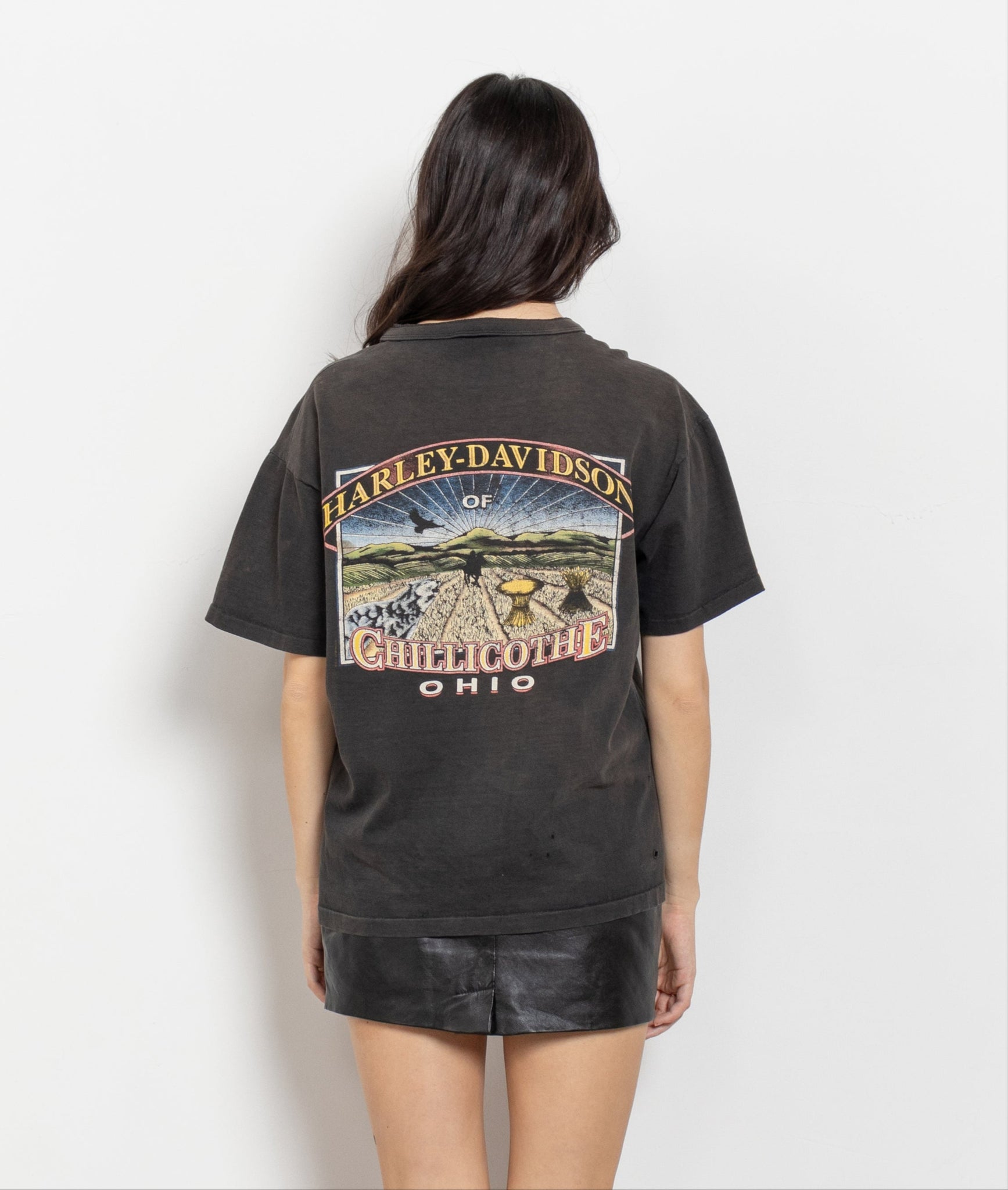 A person wearing a vintage Harley Davidson Chillicothe Ohio black t-shirt with a graphic on the back.