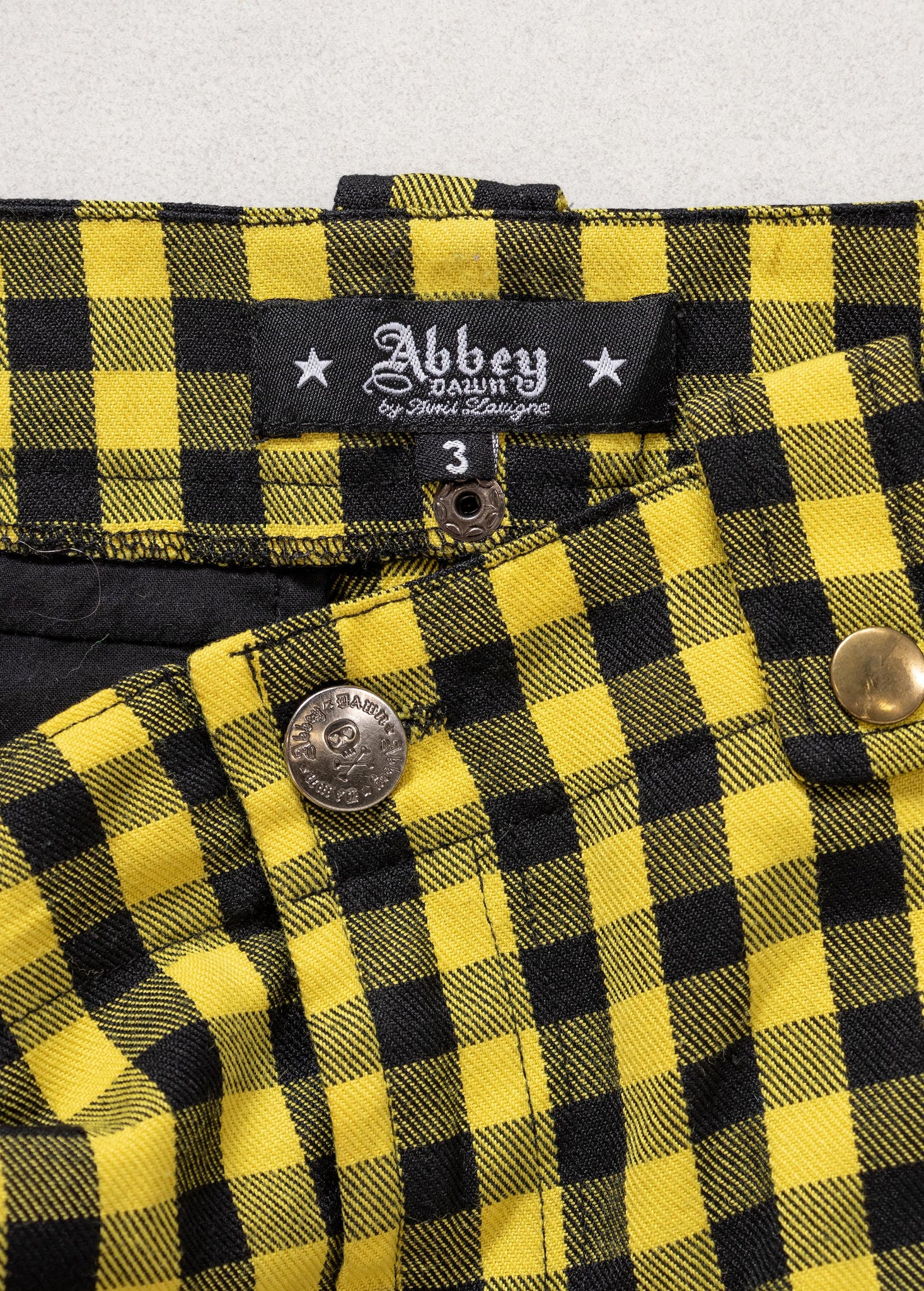 Yellow and black plaid fabric with Abbey Dawn label on a gray background
