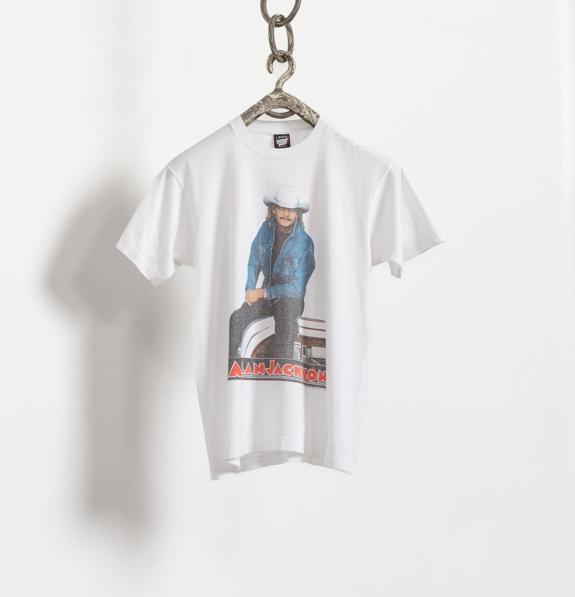 Vintage white t-shirt with a graphic print of Alan Jackson wearing a blue shirt, predominantly hung against a white background.