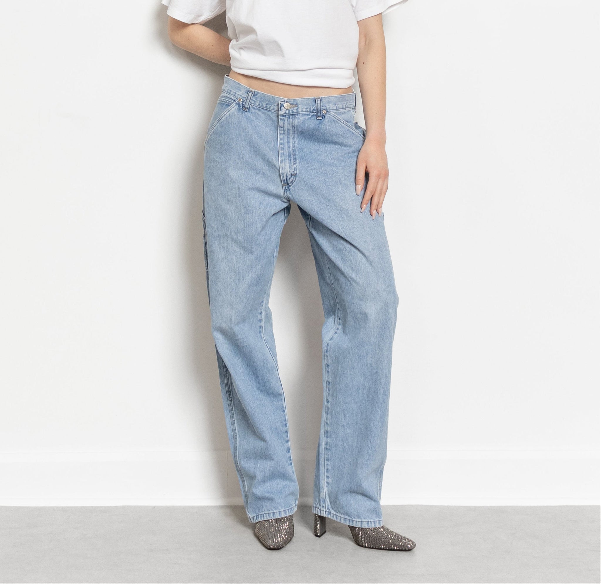 Person wearing a white t-shirt and light blue jeans on a plain background