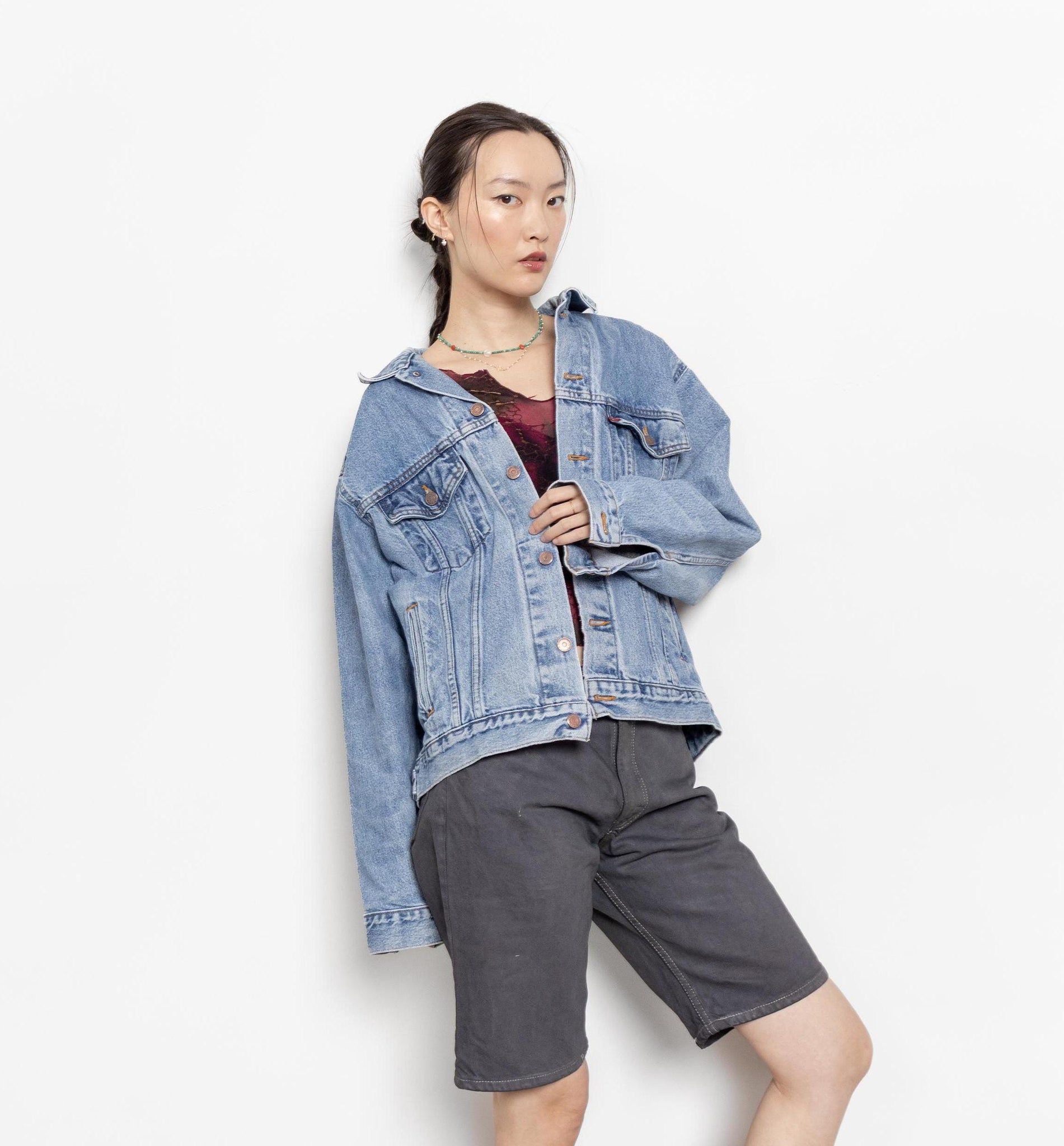 A person wearing a vintage Levi's medium wash blue denim jacket with a boxy fit, displayed in a casual setting.
