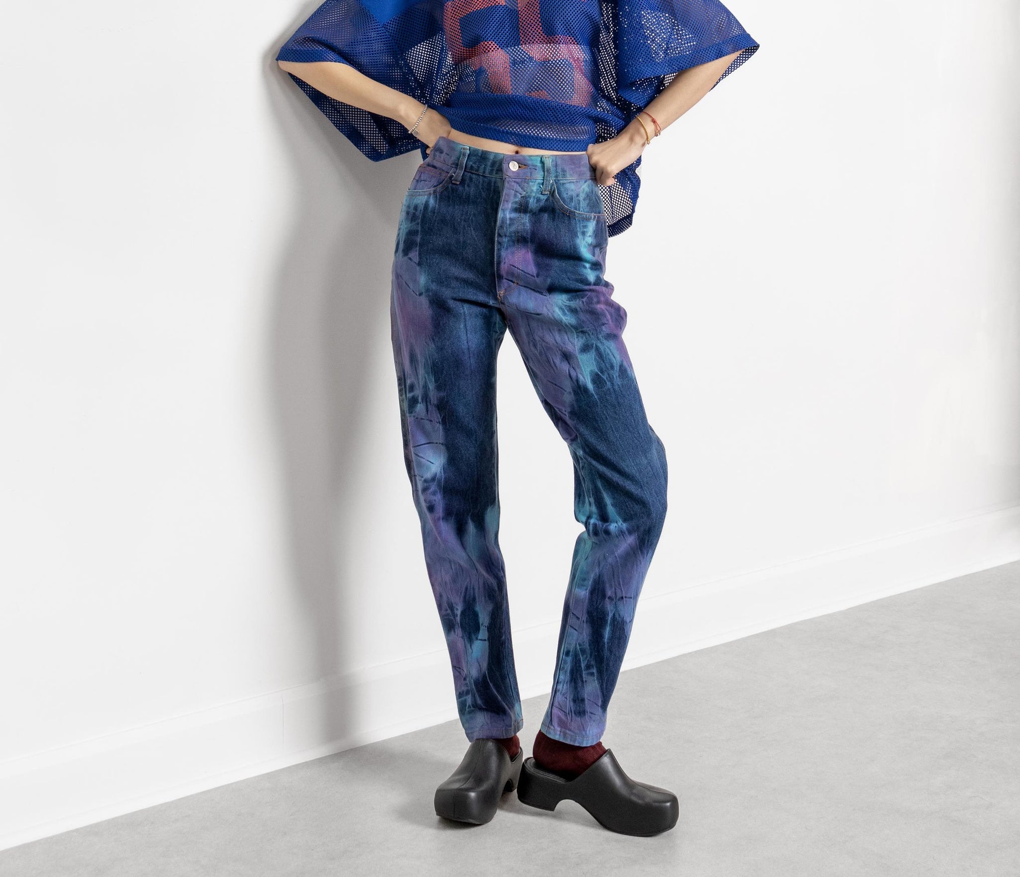 A person wearing vintage high-waisted dark wash blue tie-dye straight-leg jeans and black top.