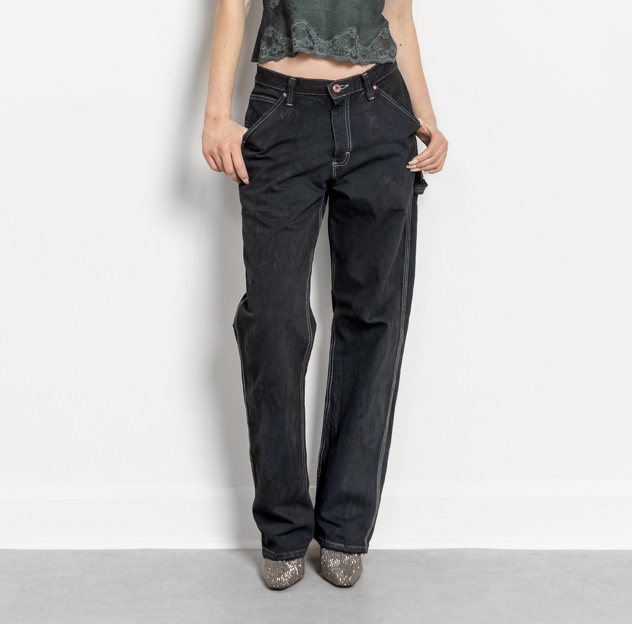 Person wearing black high-waisted jeans on a plain background