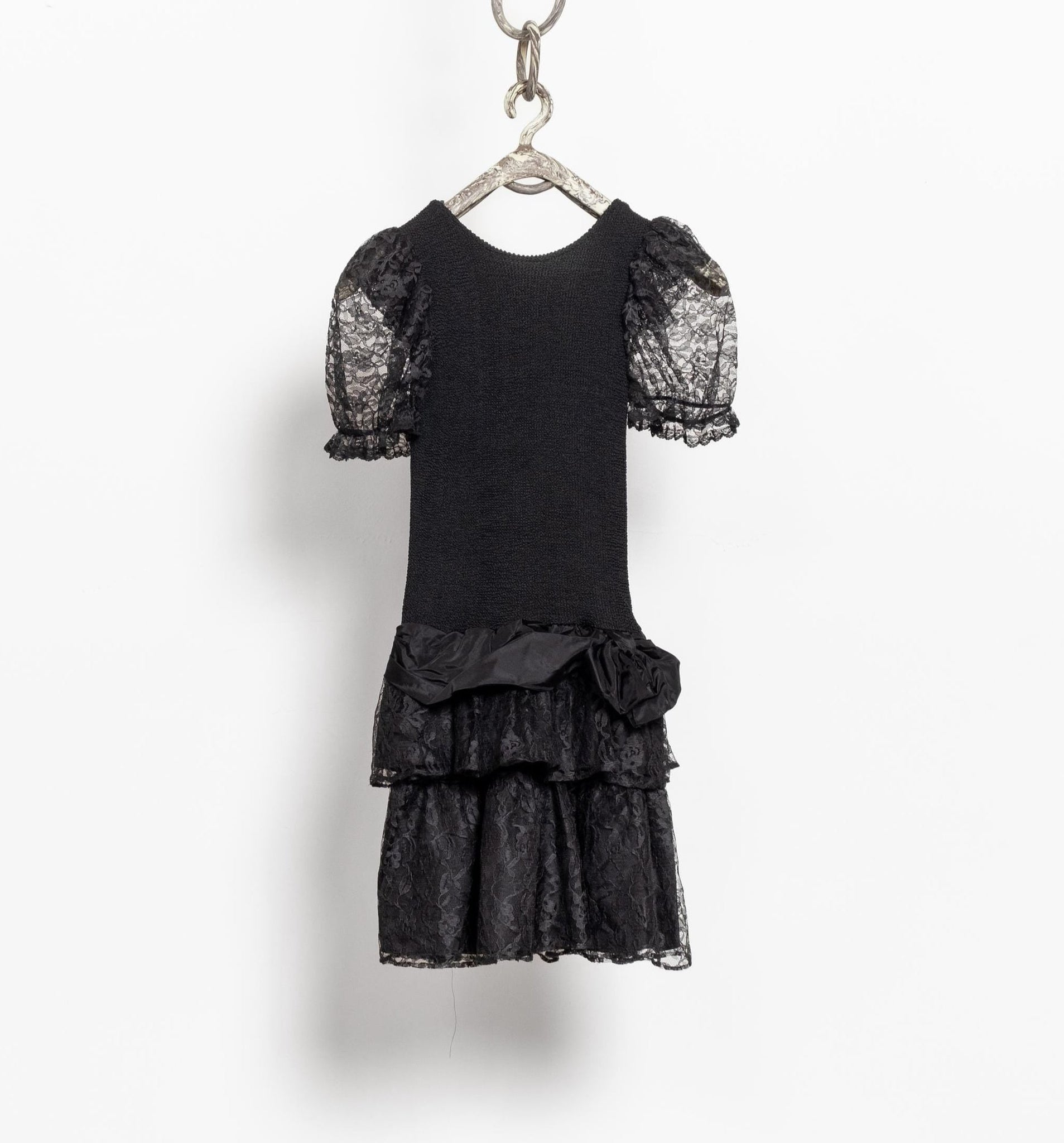 Black lace dress on a hanger against a white background
