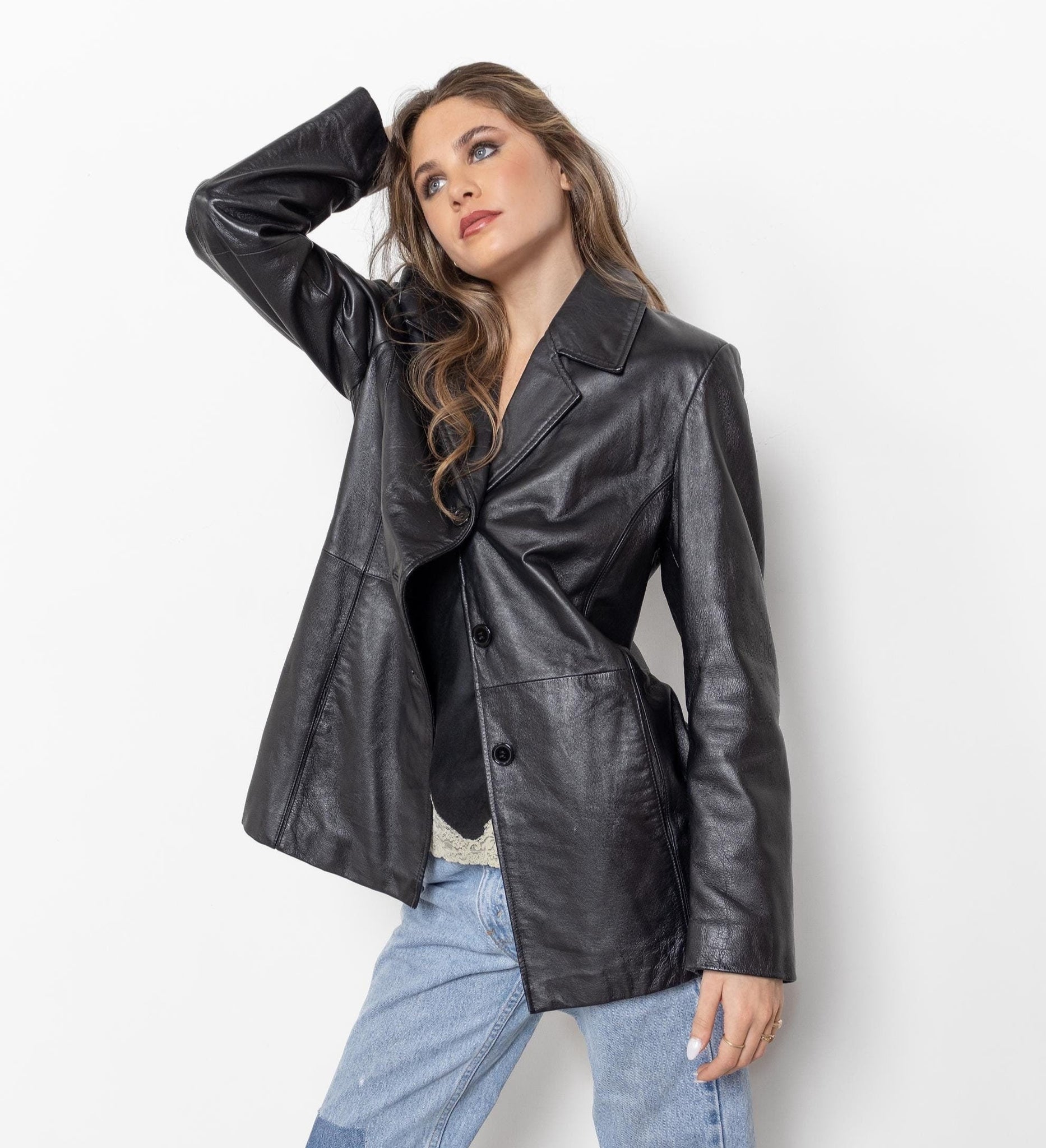 Woman wearing a black leather jacket and blue jeans against a white background
