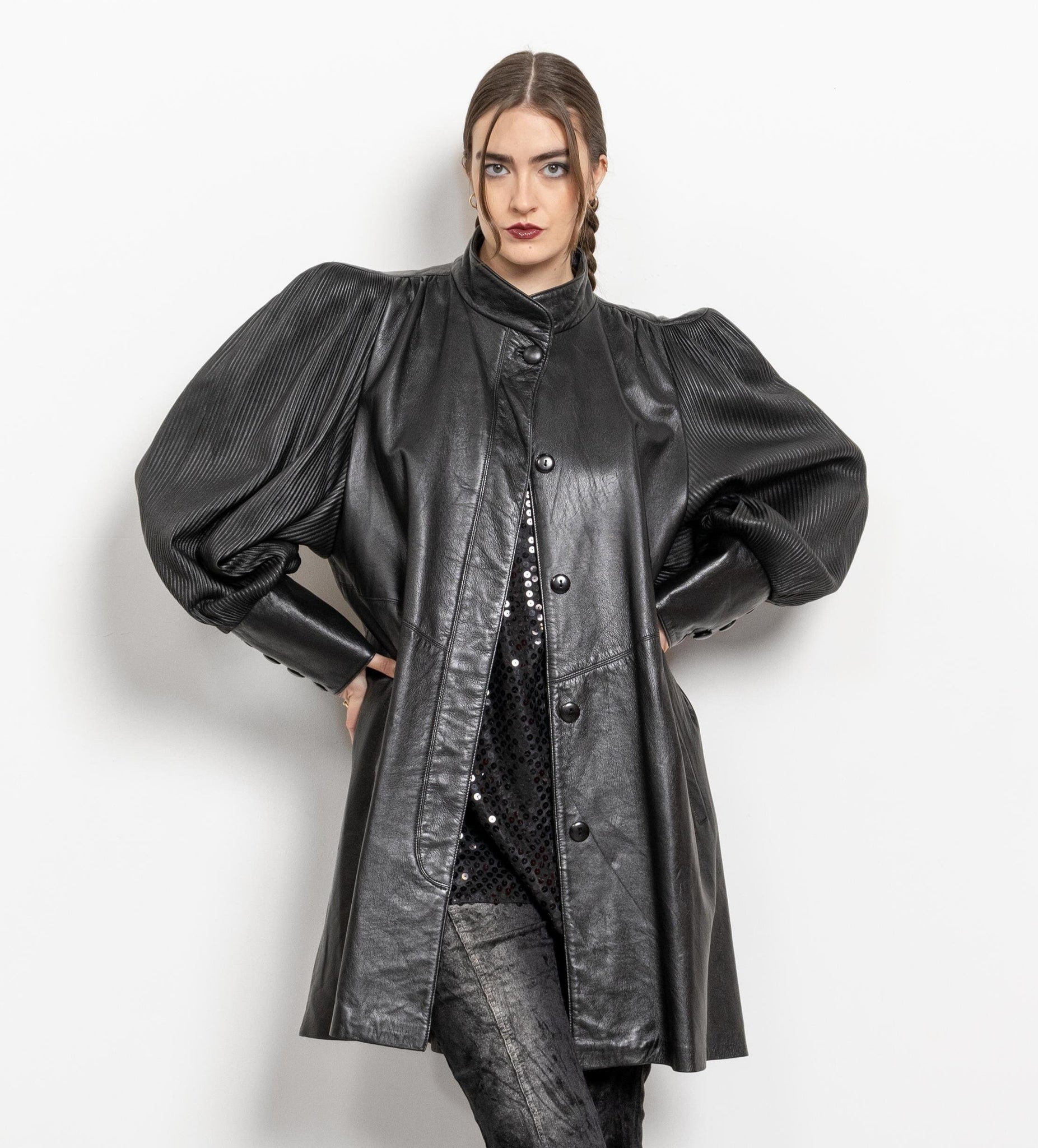 Person wearing a black leather coat with puffed sleeves on a white background