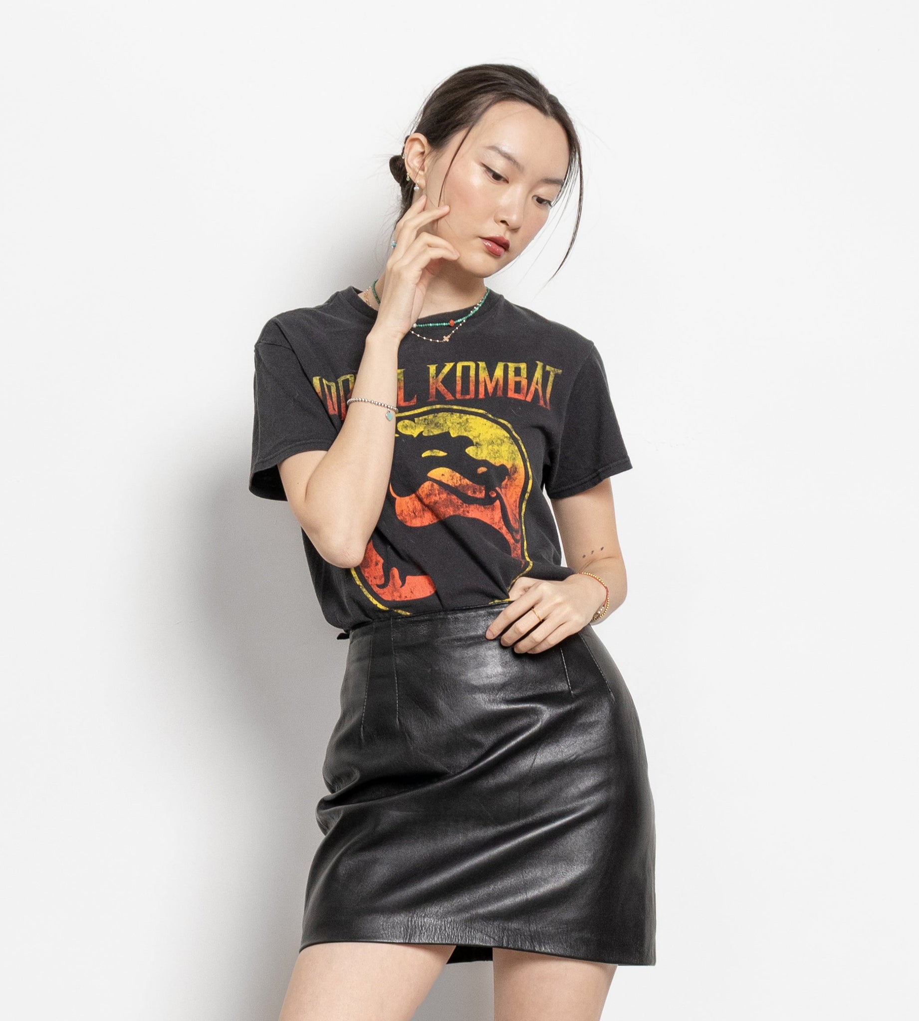 Person wearing a graphic t-shirt and black leather skirt on a white background