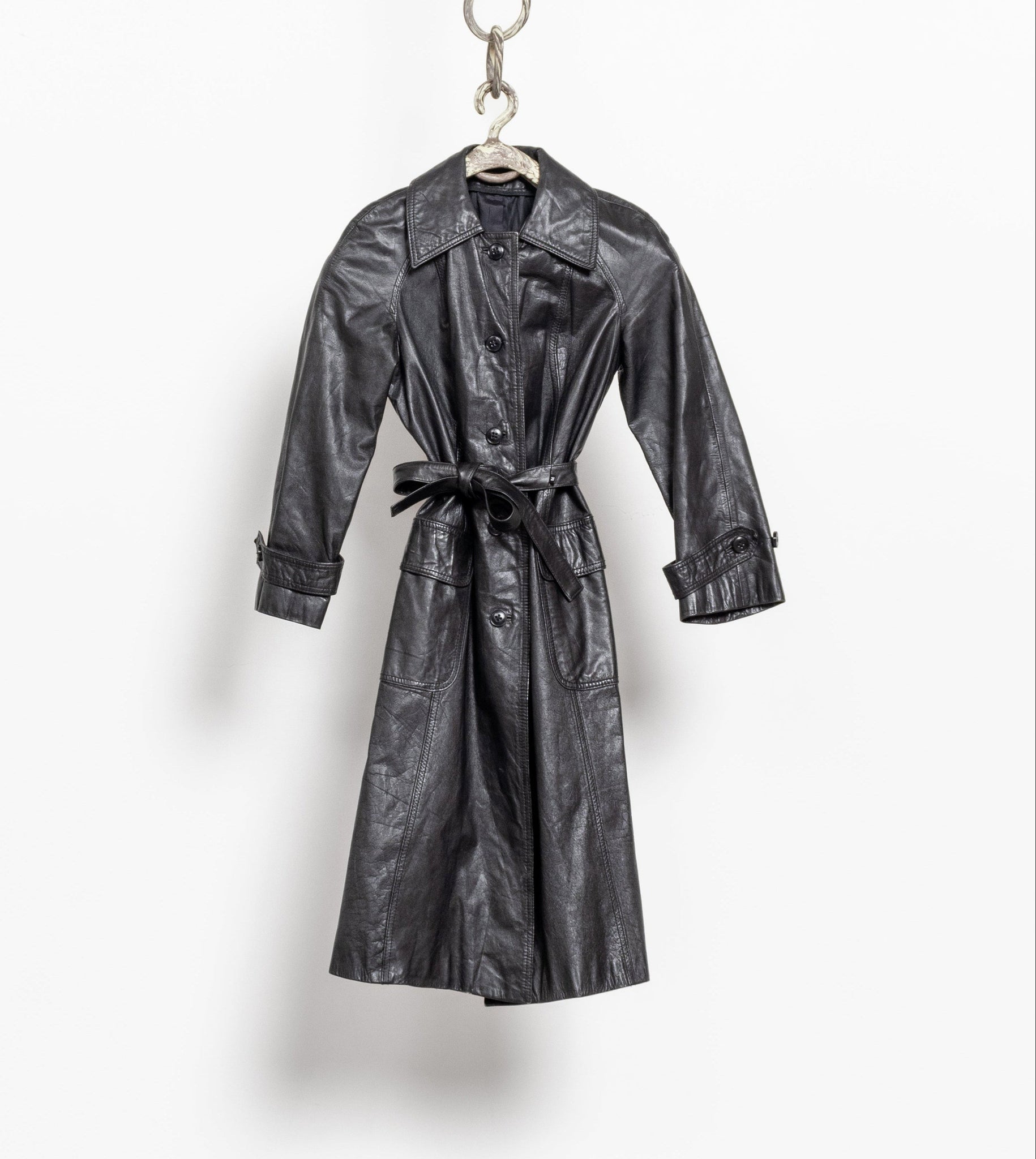Black leather trench coat hanging on a white background