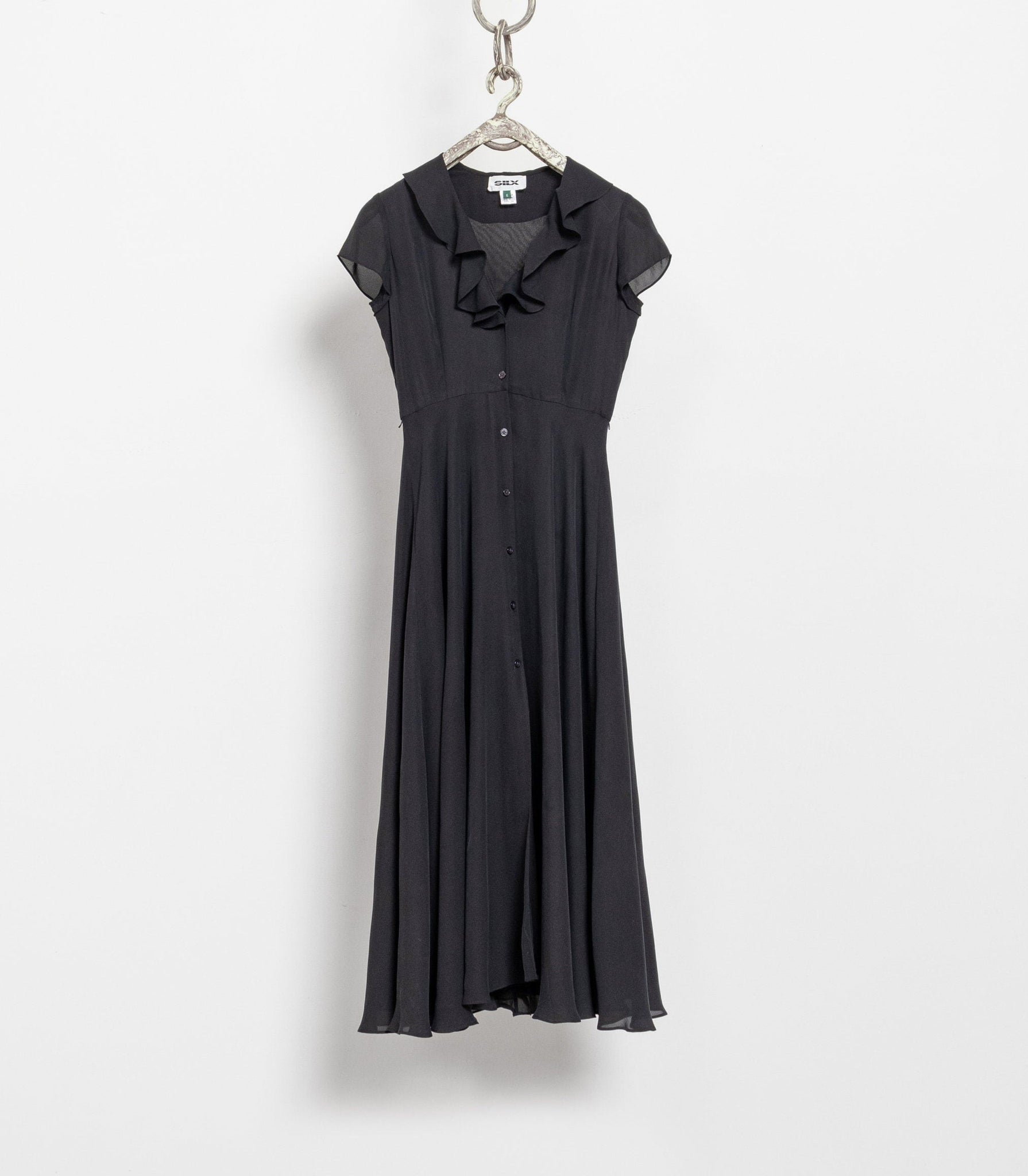 A vintage black silk dress with a ruffled neckline and buttons down the front, displayed on a hanger against a white background.