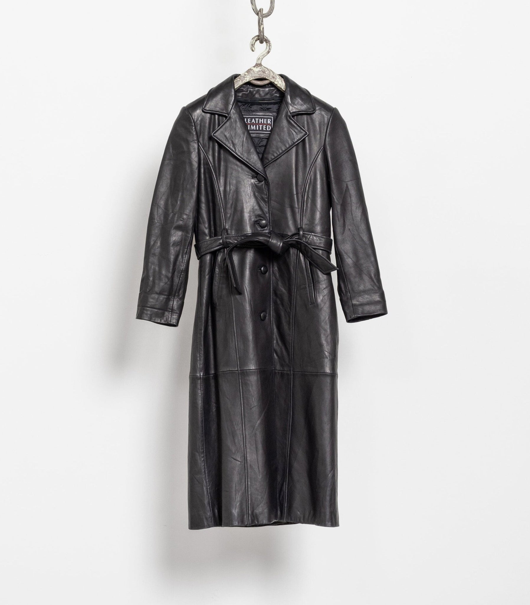 Black leather trench coat hanging on a white background