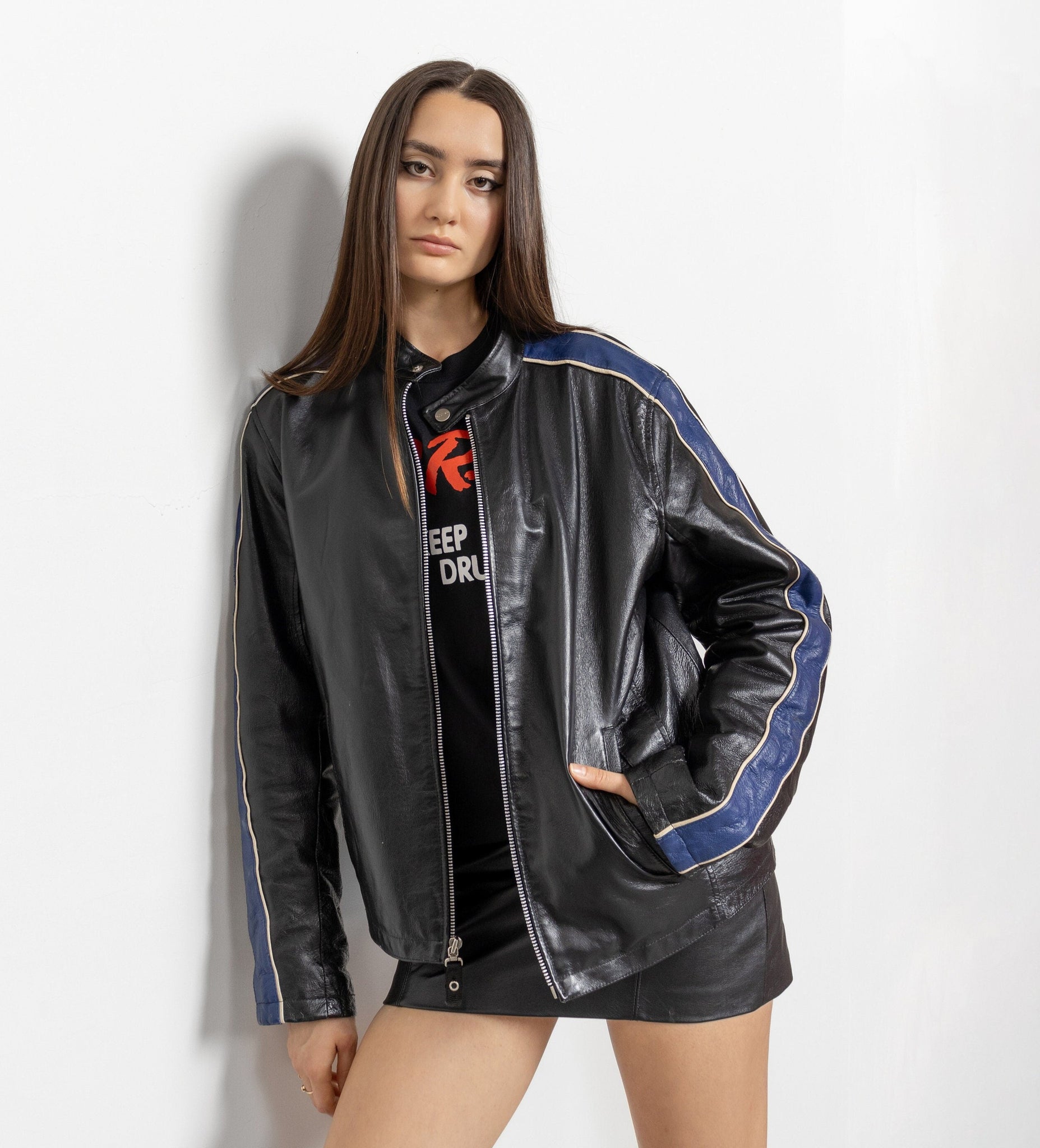 Person wearing a black leather jacket with blue accents on a white background