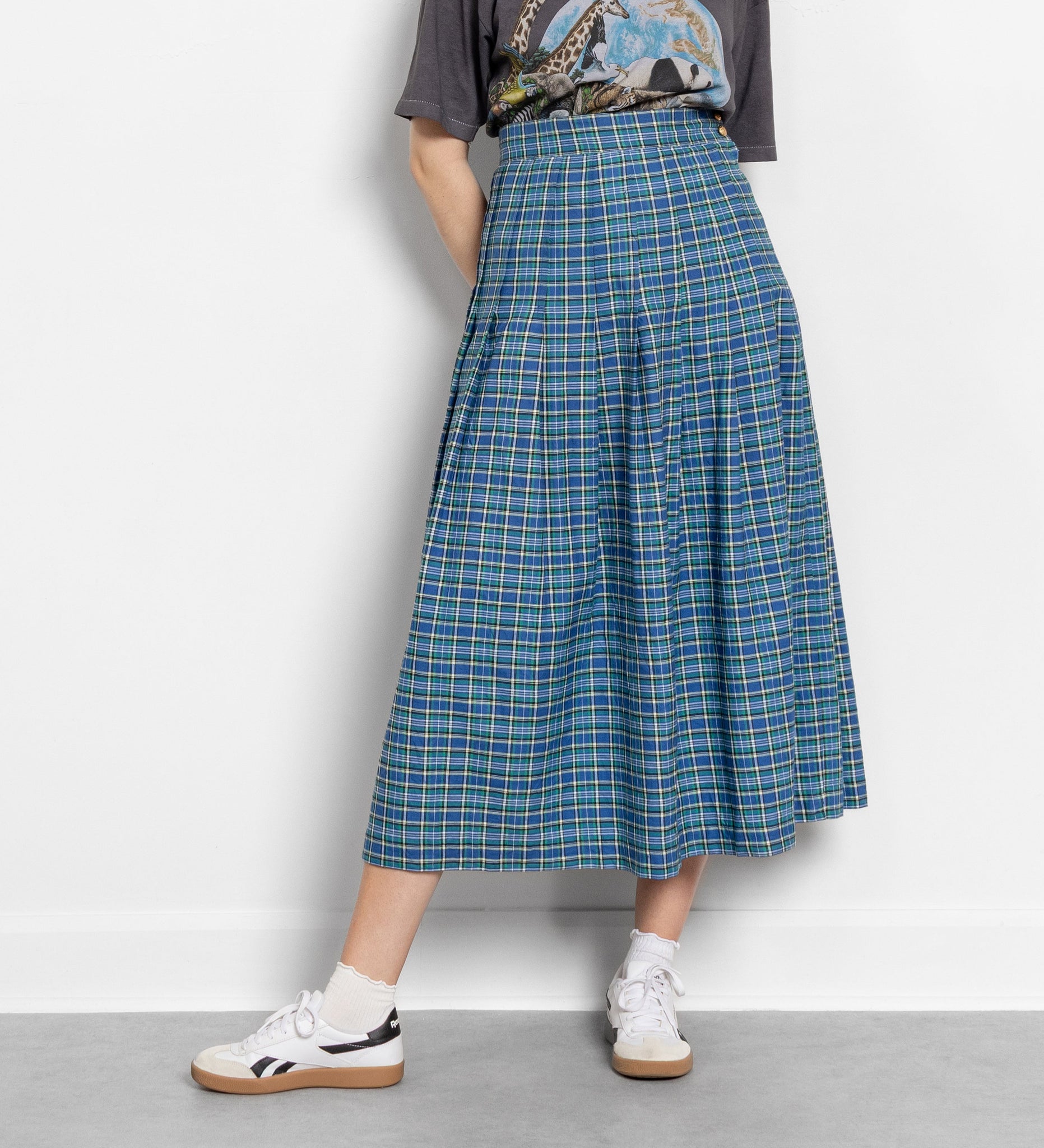 Woman wearing a graphic t-shirt and plaid skirt on a white background