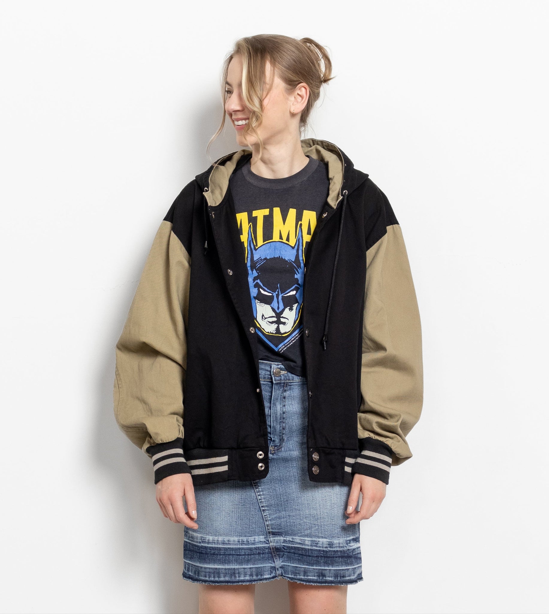 Person wearing a two-tone jacket with a graphic t-shirt and denim skirt on a white background