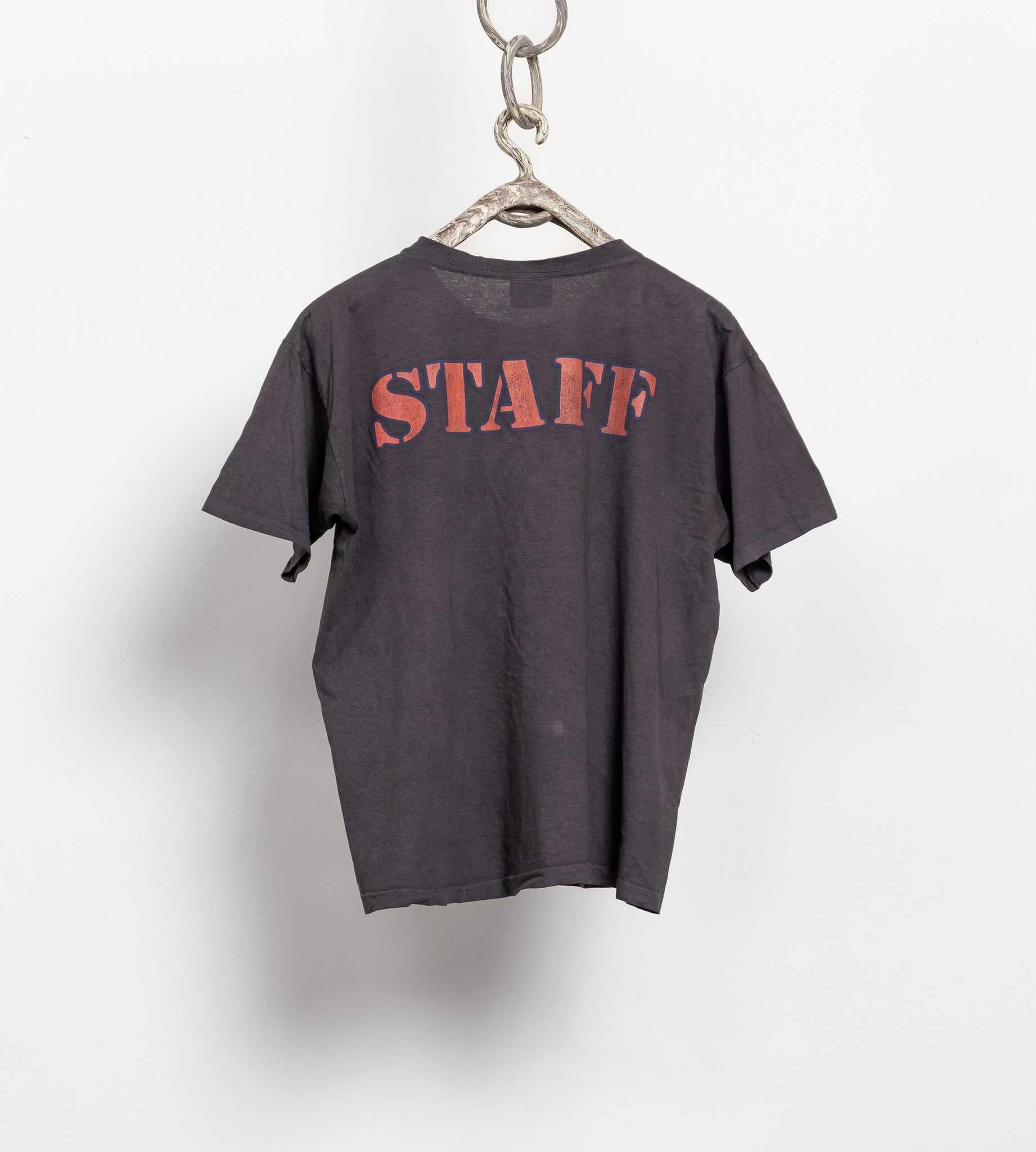 Gray t-shirt with 'STAFF' printed on it, hanging on a white background