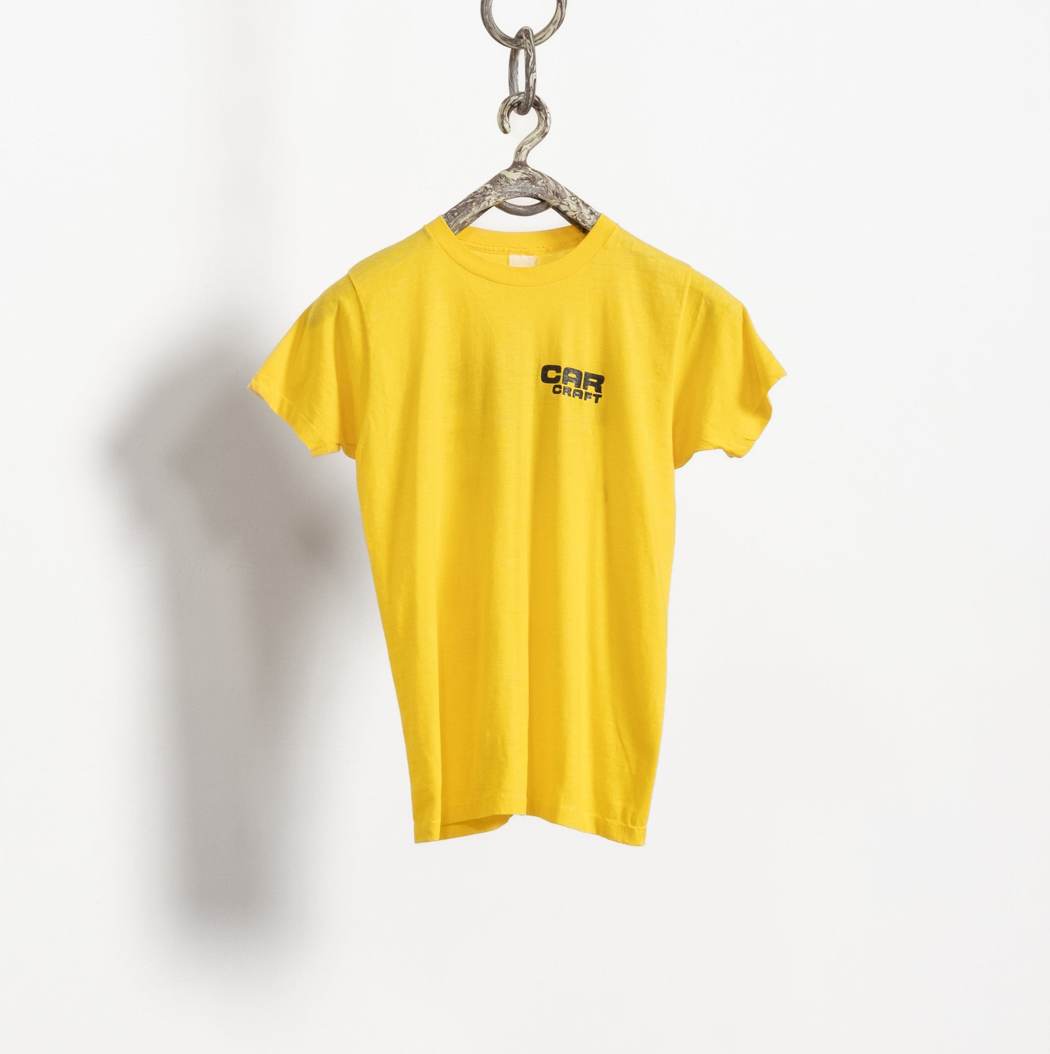 Yellow t-shirt with a logo on a hanger against a white background