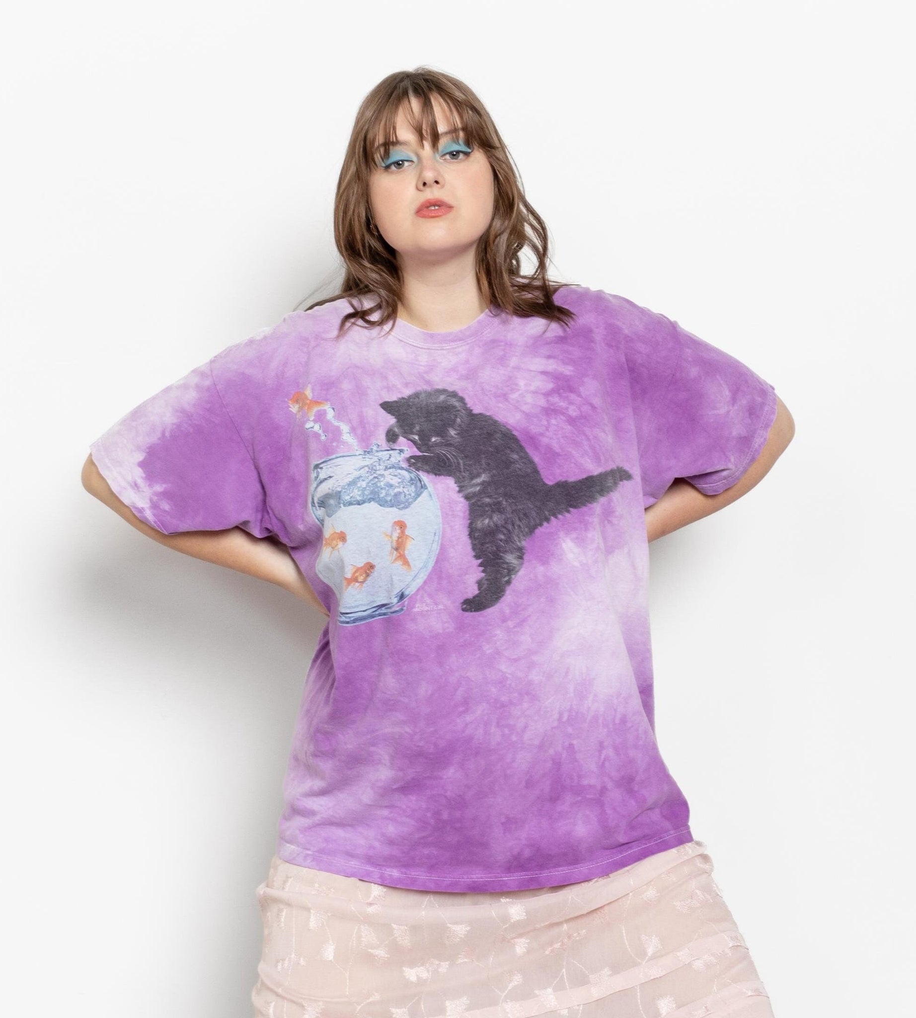 Person wearing a purple tie-dye t-shirt with a graphic design, standing against a white background