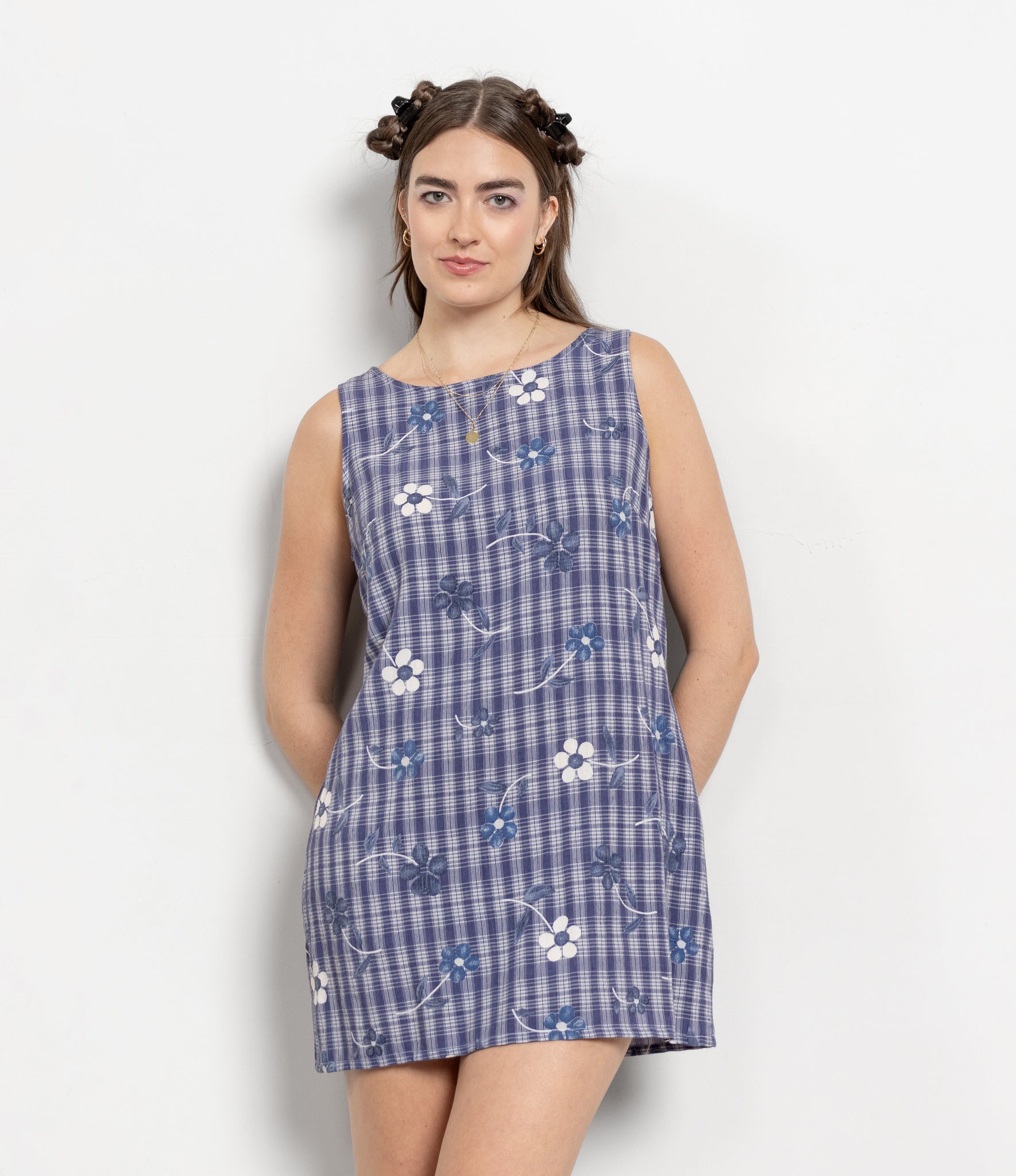 Woman wearing a blue checkered dress with floral patterns on a white background