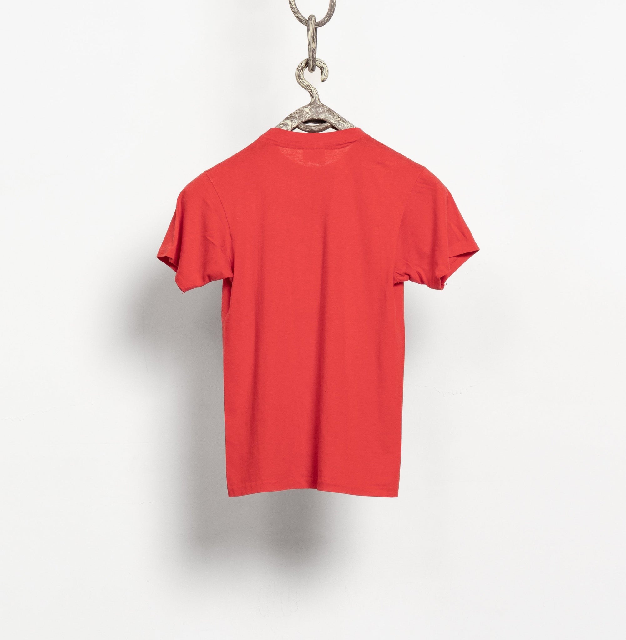 Red t-shirt hanging on a hook against a white background