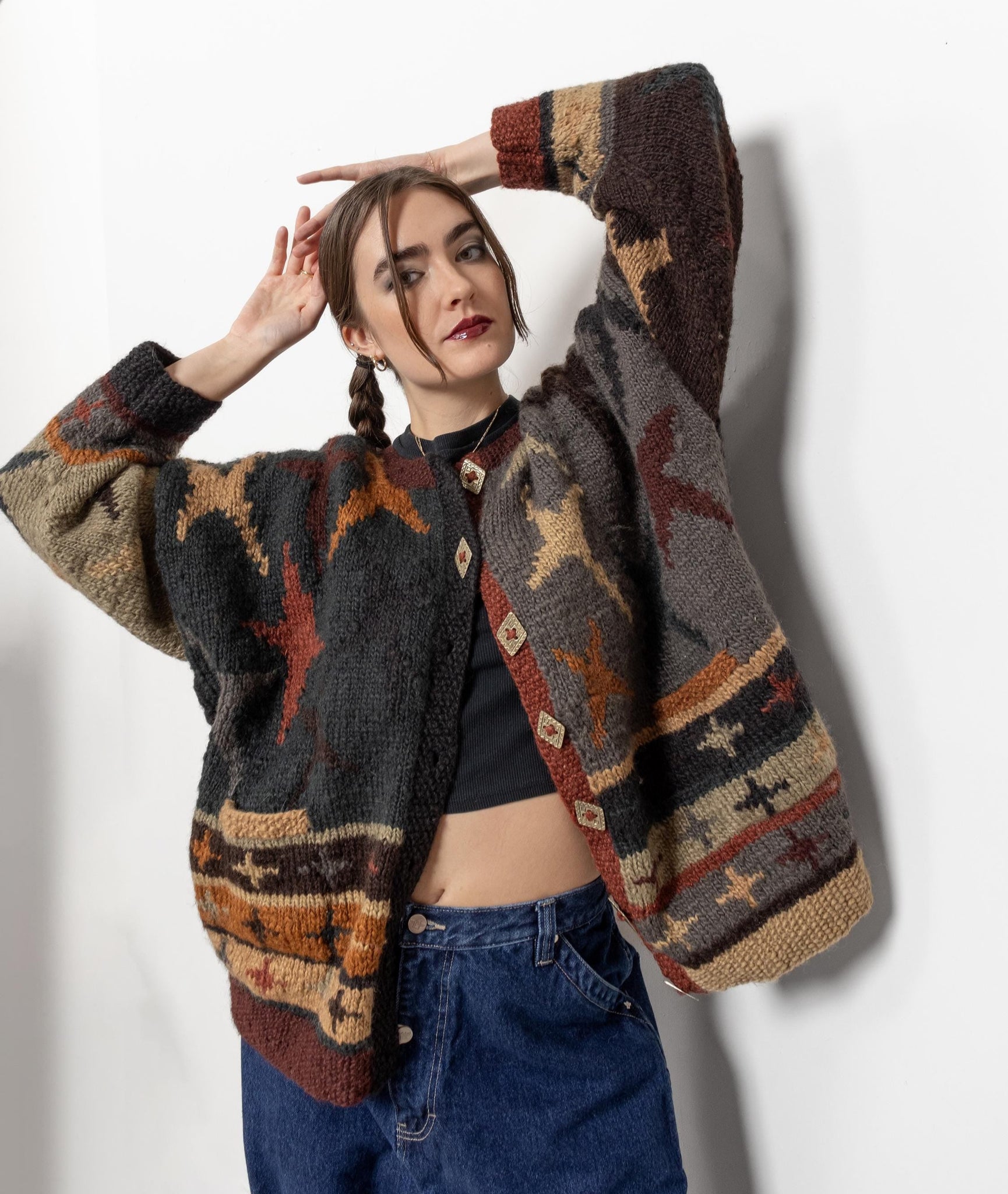 A person wearing a vintage 90's knit button-up cardigan with a pattern of stars and colorblocking in various colors.