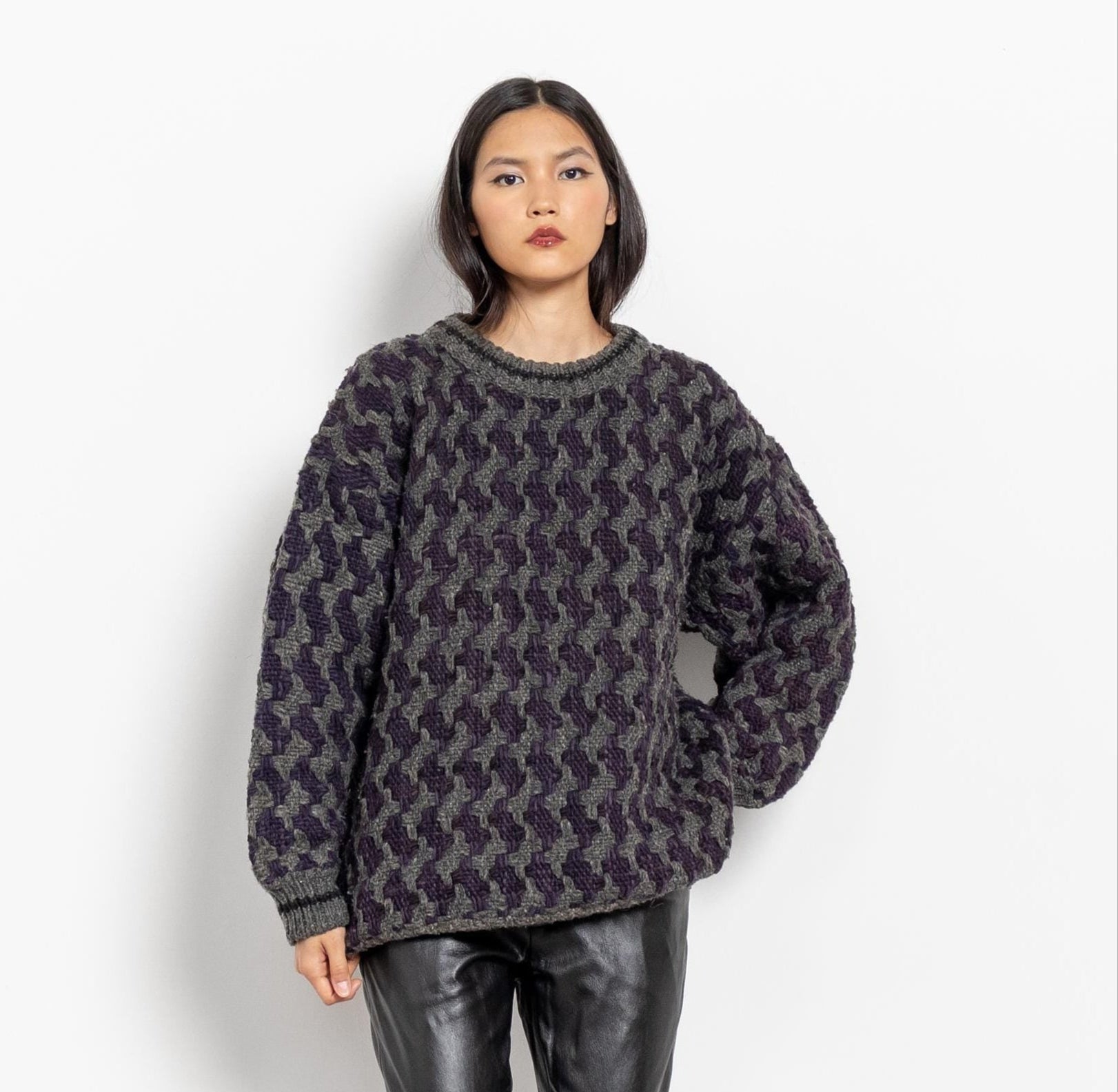 Person wearing a patterned sweater on a plain background