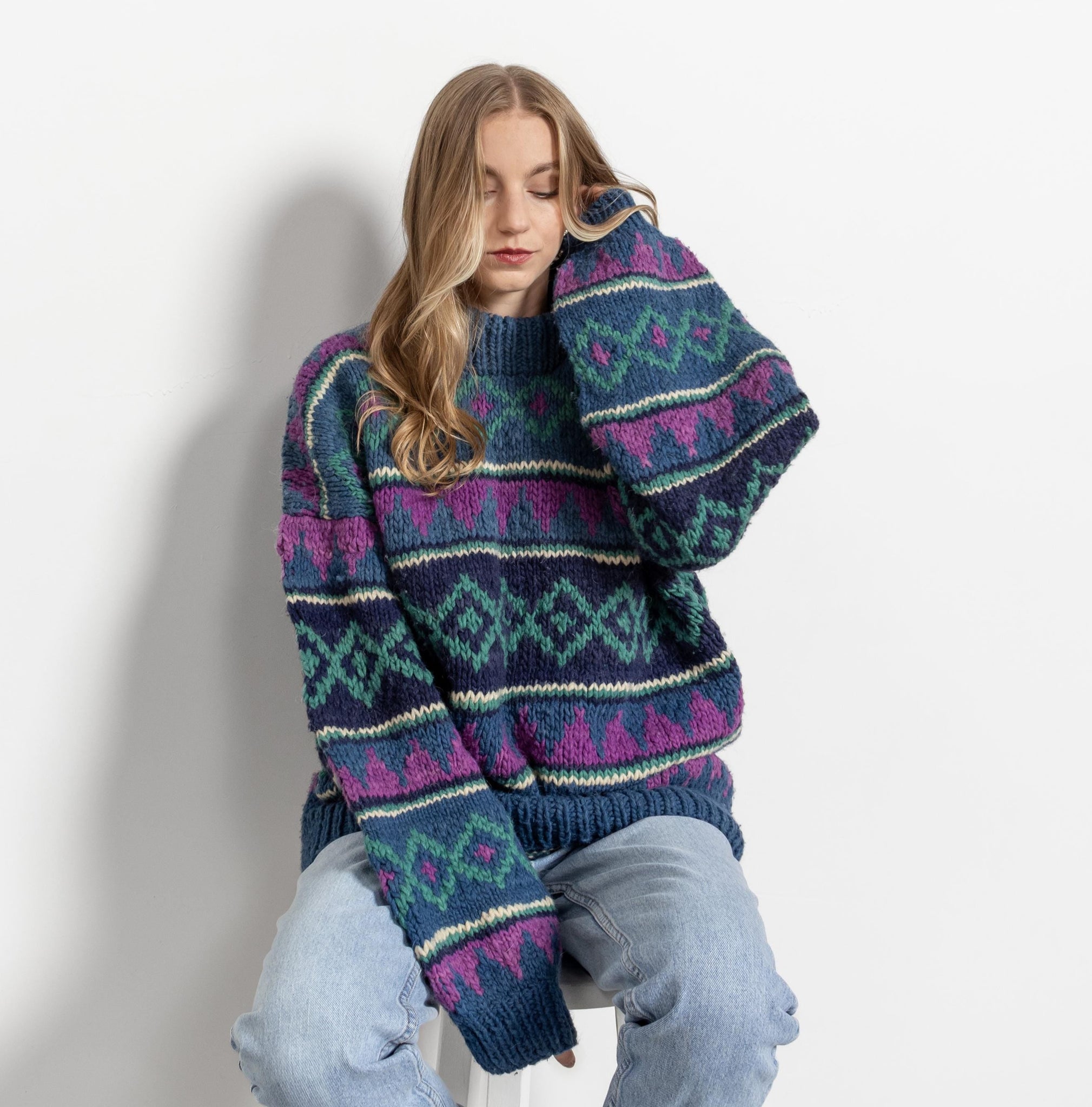 Woman wearing a patterned sweater sitting on a white surface