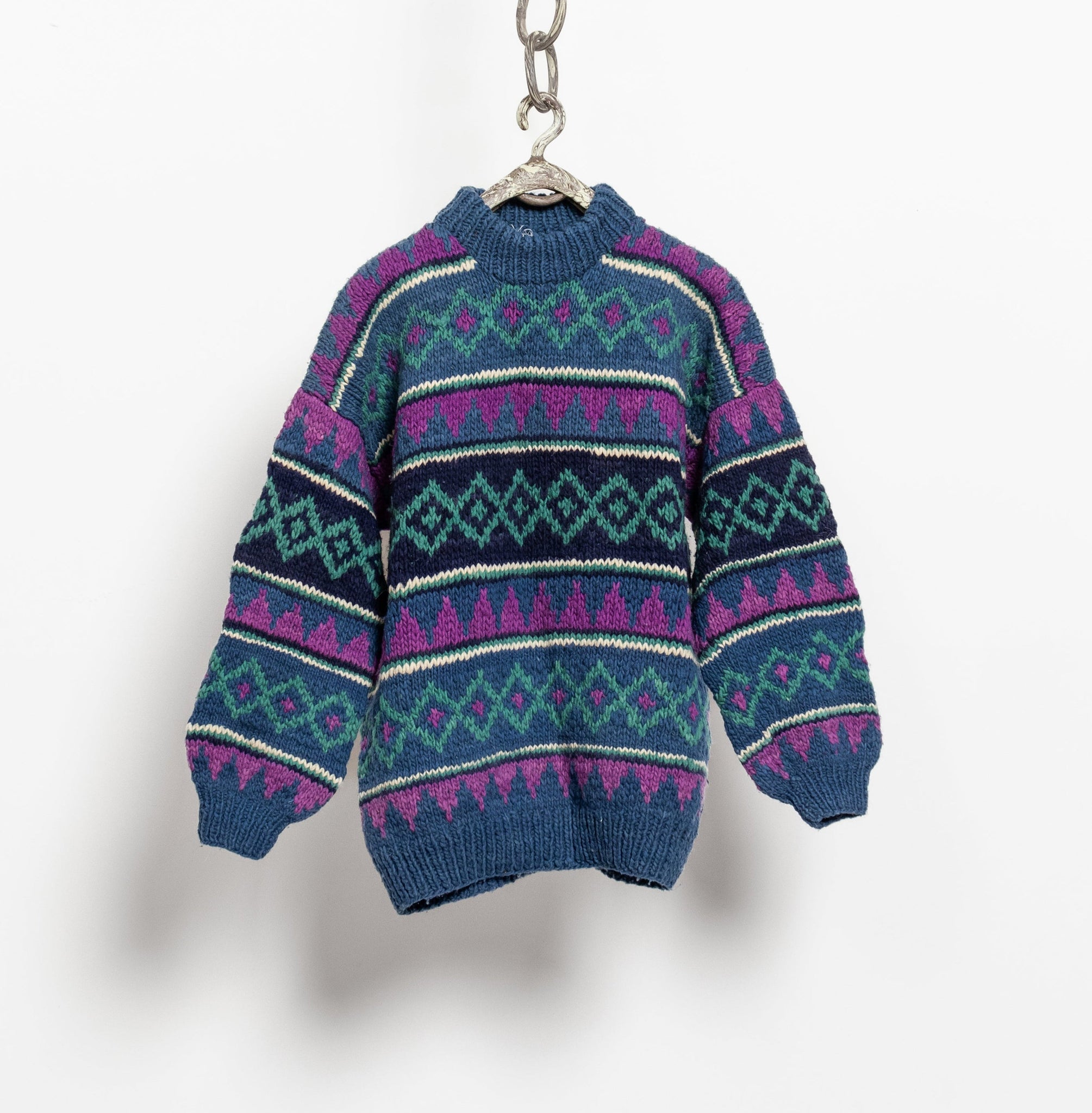 Blue and purple patterned sweater on a hanger against a white background