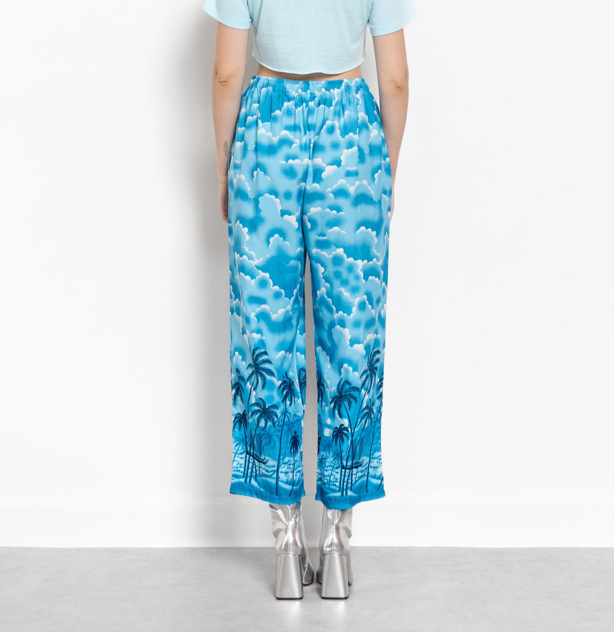 Person wearing a light blue top and blue patterned pants against a white background