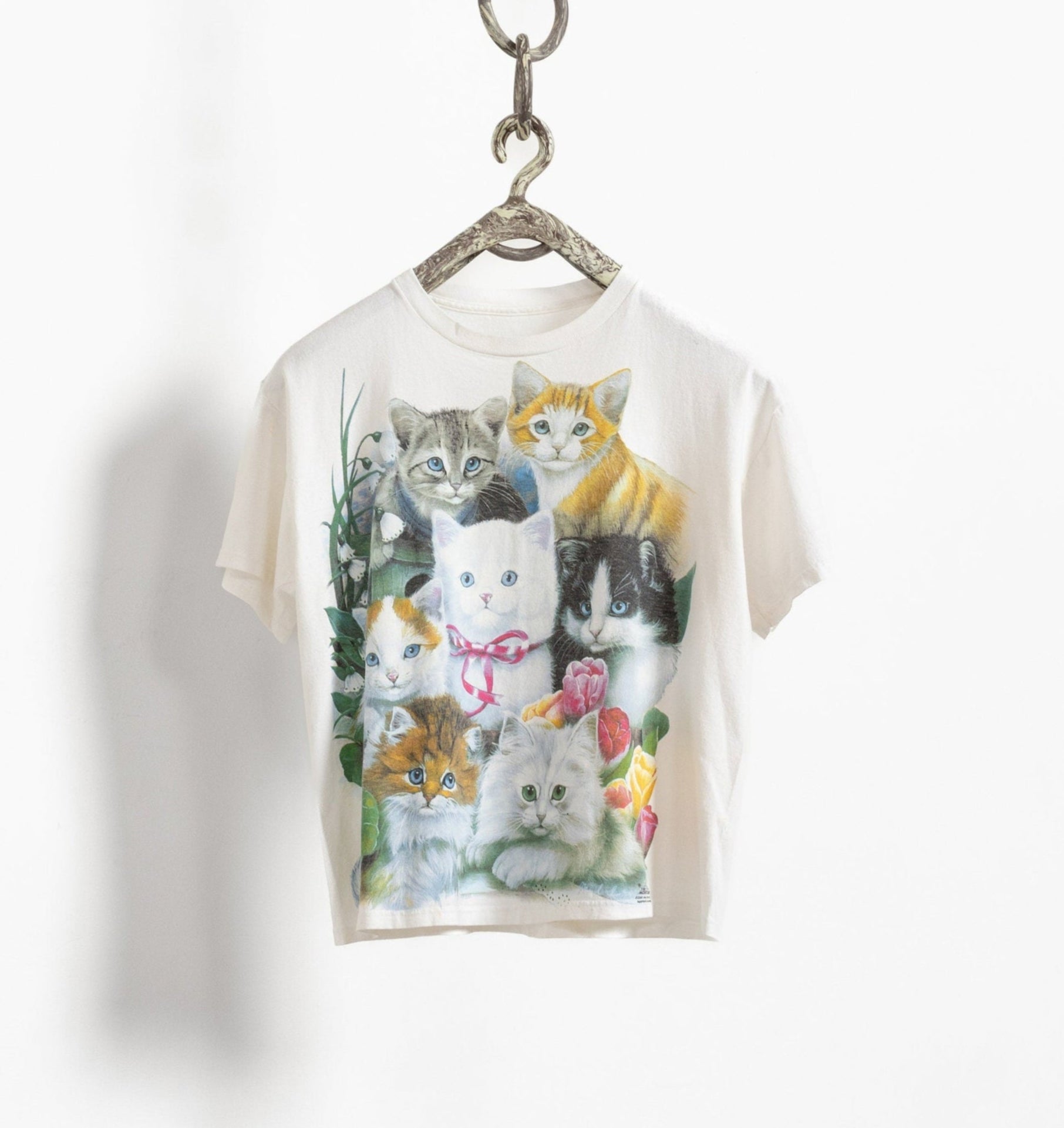 T-shirt with cat illustrations on a hanger against a white background
