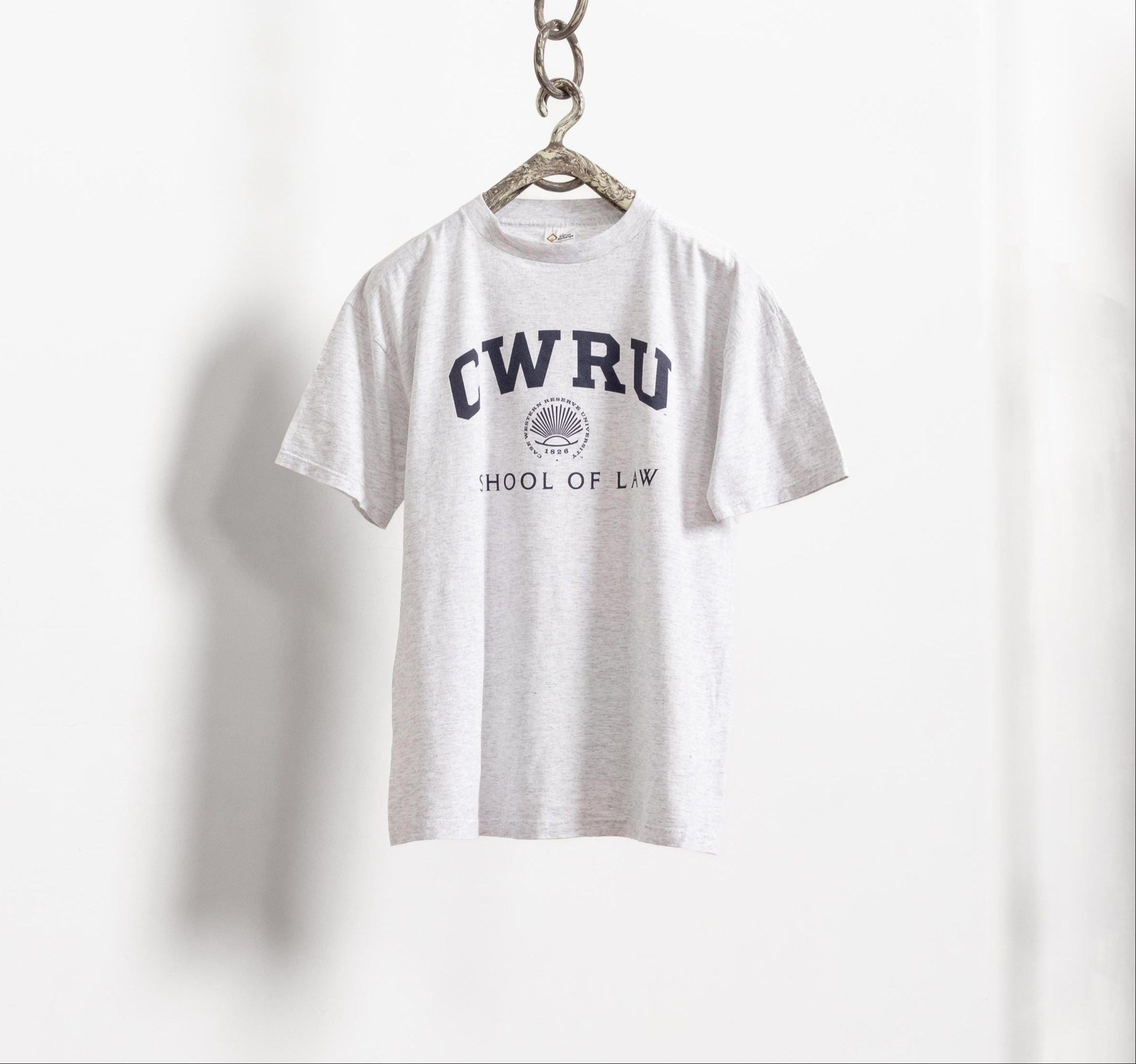 A gray vintage CWRU (Case Western Reserve University) t-shirt hanging on a hanger against a white background, with the text 'CWRU' and 'HOME OF THE' printed on the front.
