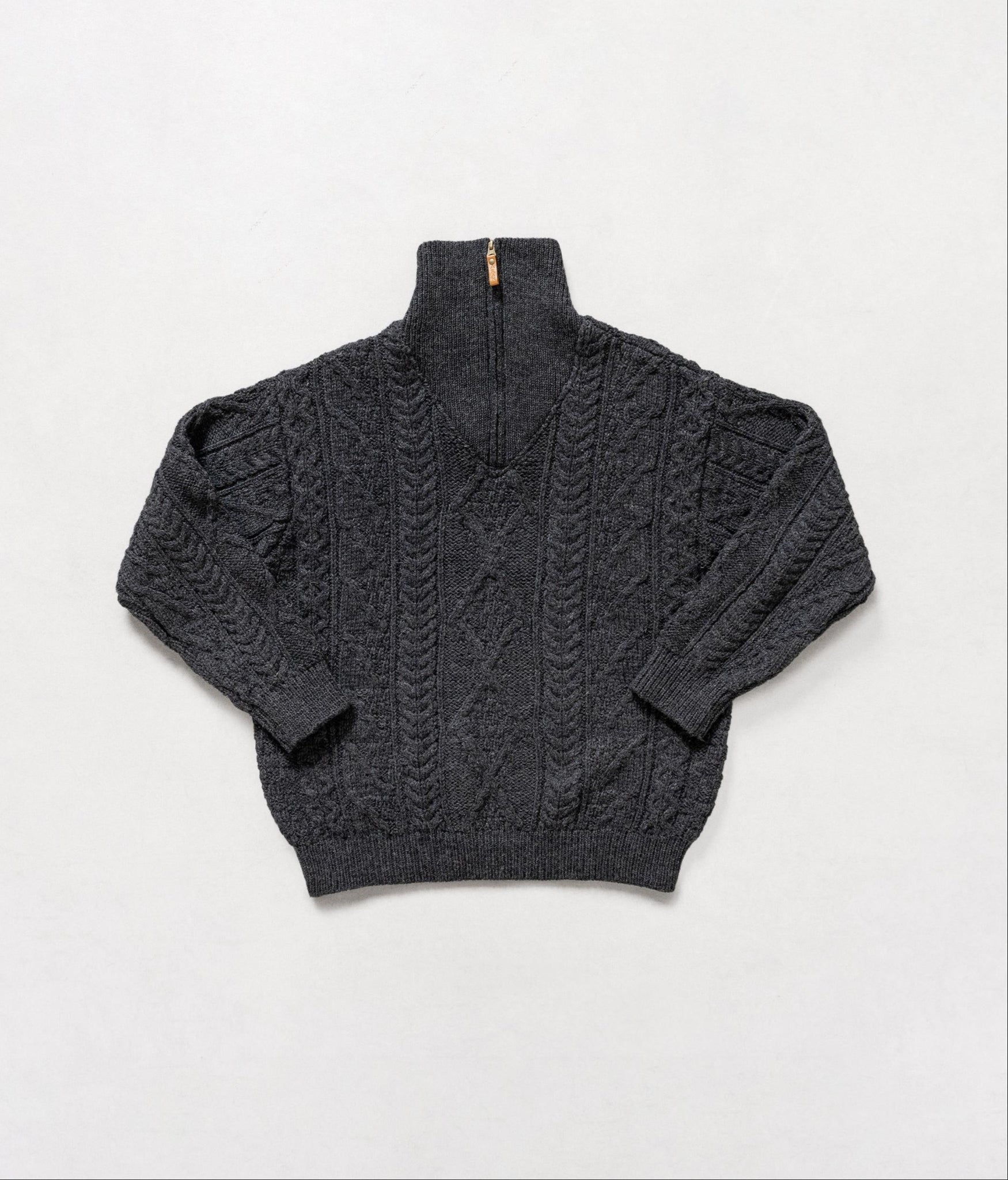 Dark gray cable knit sweater on a light gray background