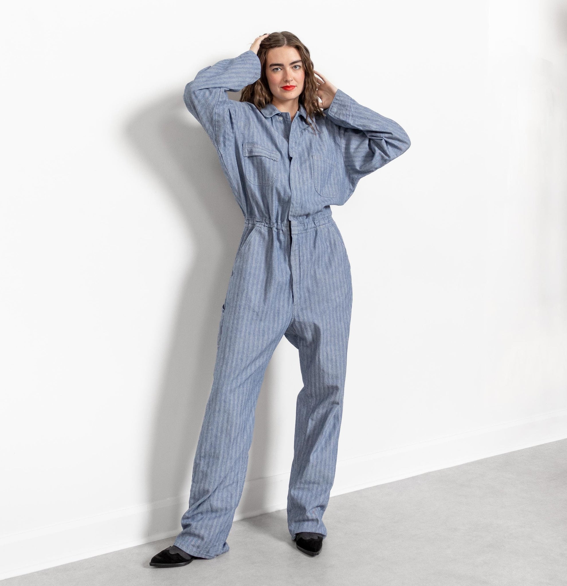 Person wearing a blue striped jumpsuit against a white background
