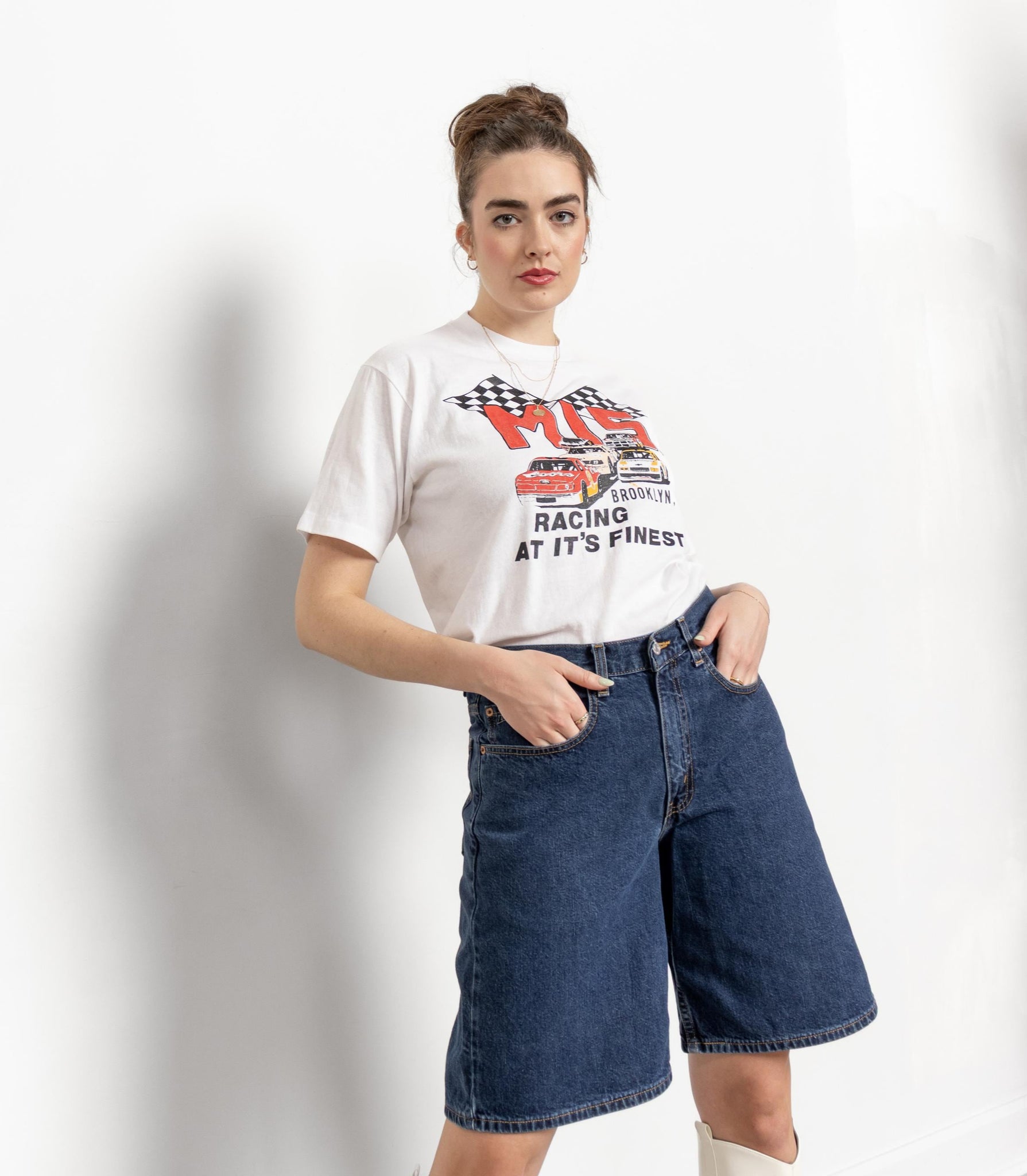 Woman wearing a graphic t-shirt and denim shorts on a white background