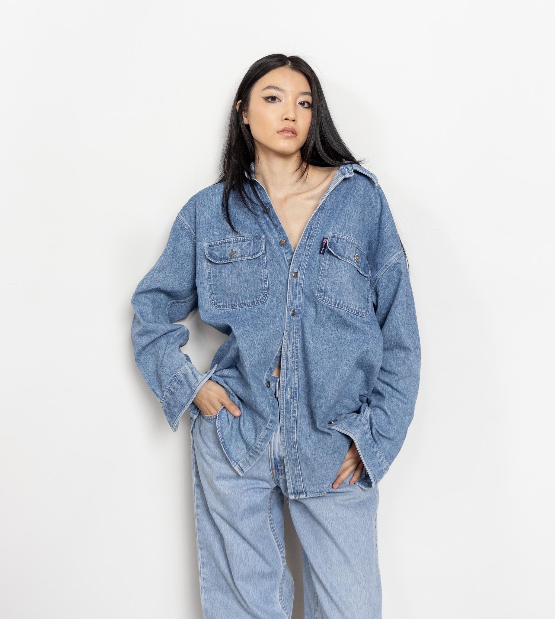 Person wearing a light blue denim outfit on a white background