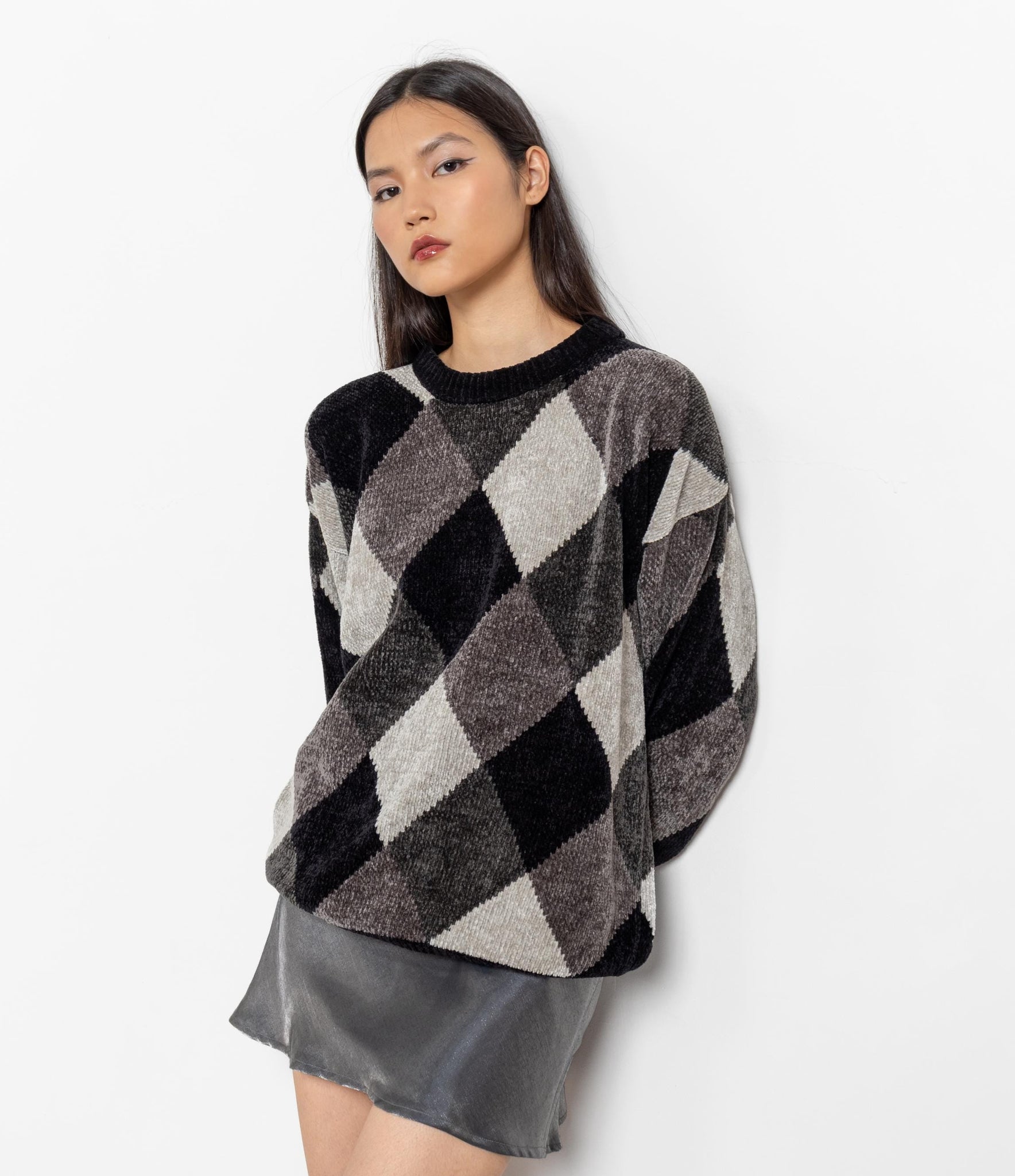 Woman wearing a black and gray argyle sweater on a white background