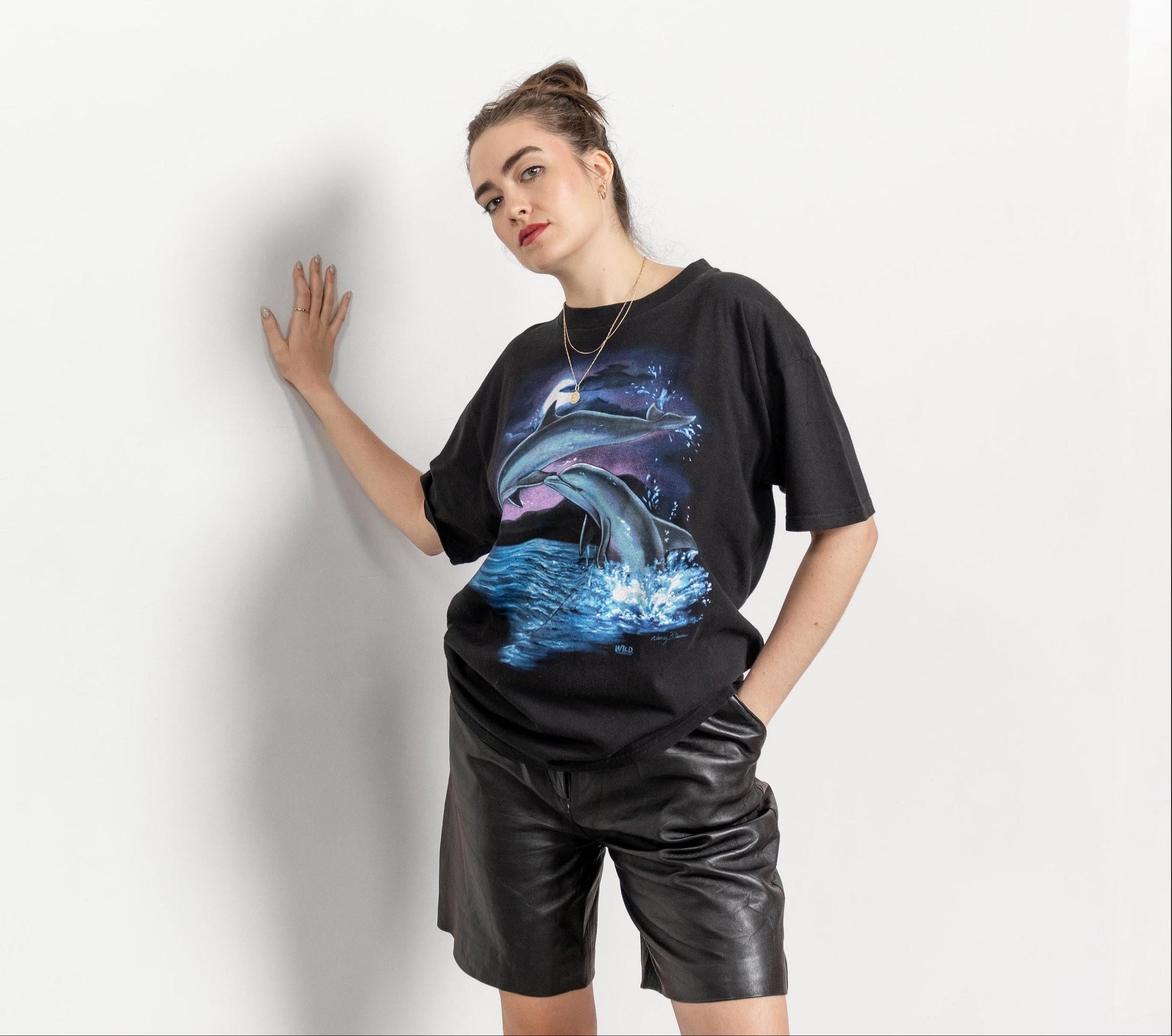 Person wearing a black t-shirt with a dolphin graphic on a plain background