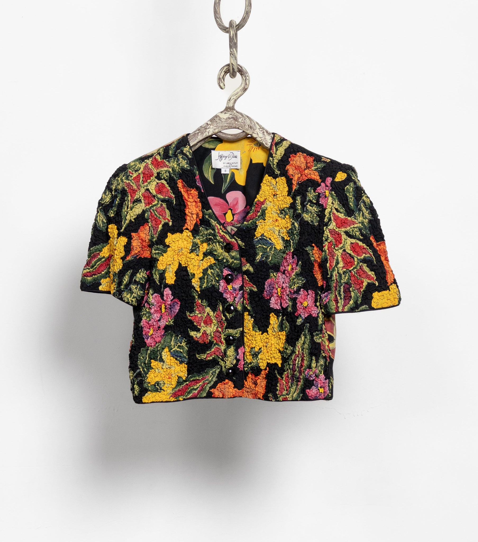 Colorful floral-patterned shirt on a hanger against a white background