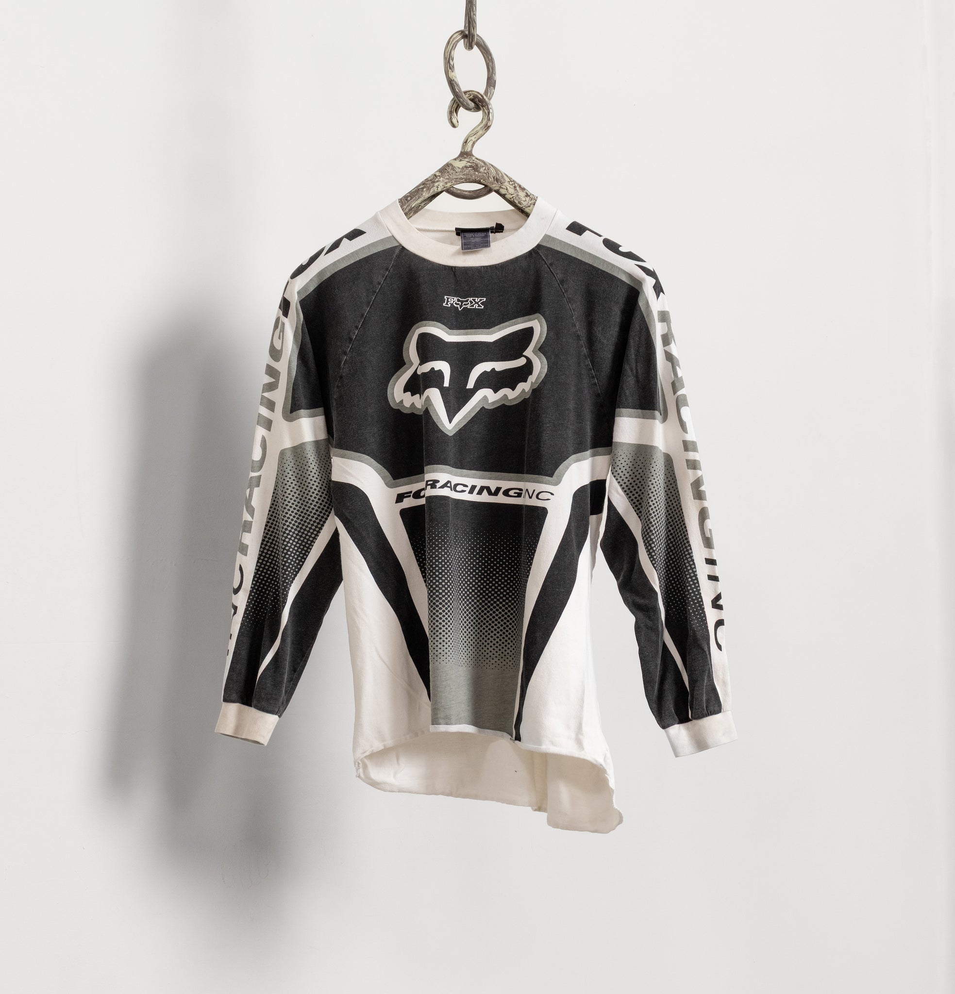 Black and white racing jersey with a brand logo on a hanger against a light gray background