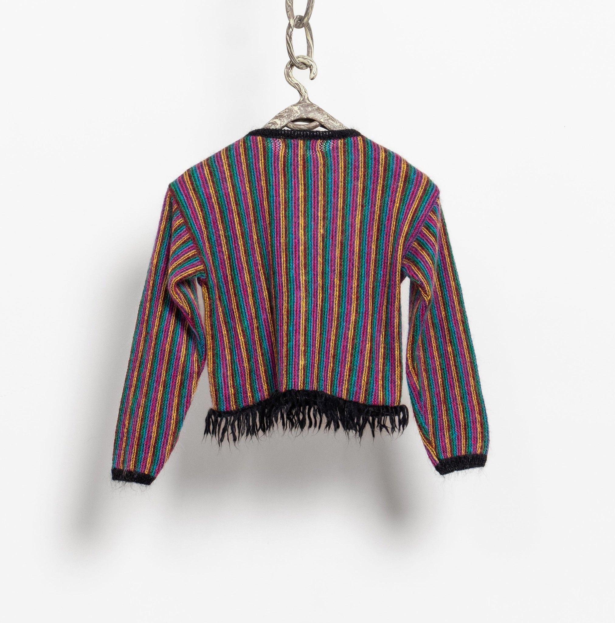 Colorful striped sweater with fringes on a hanger against a white background