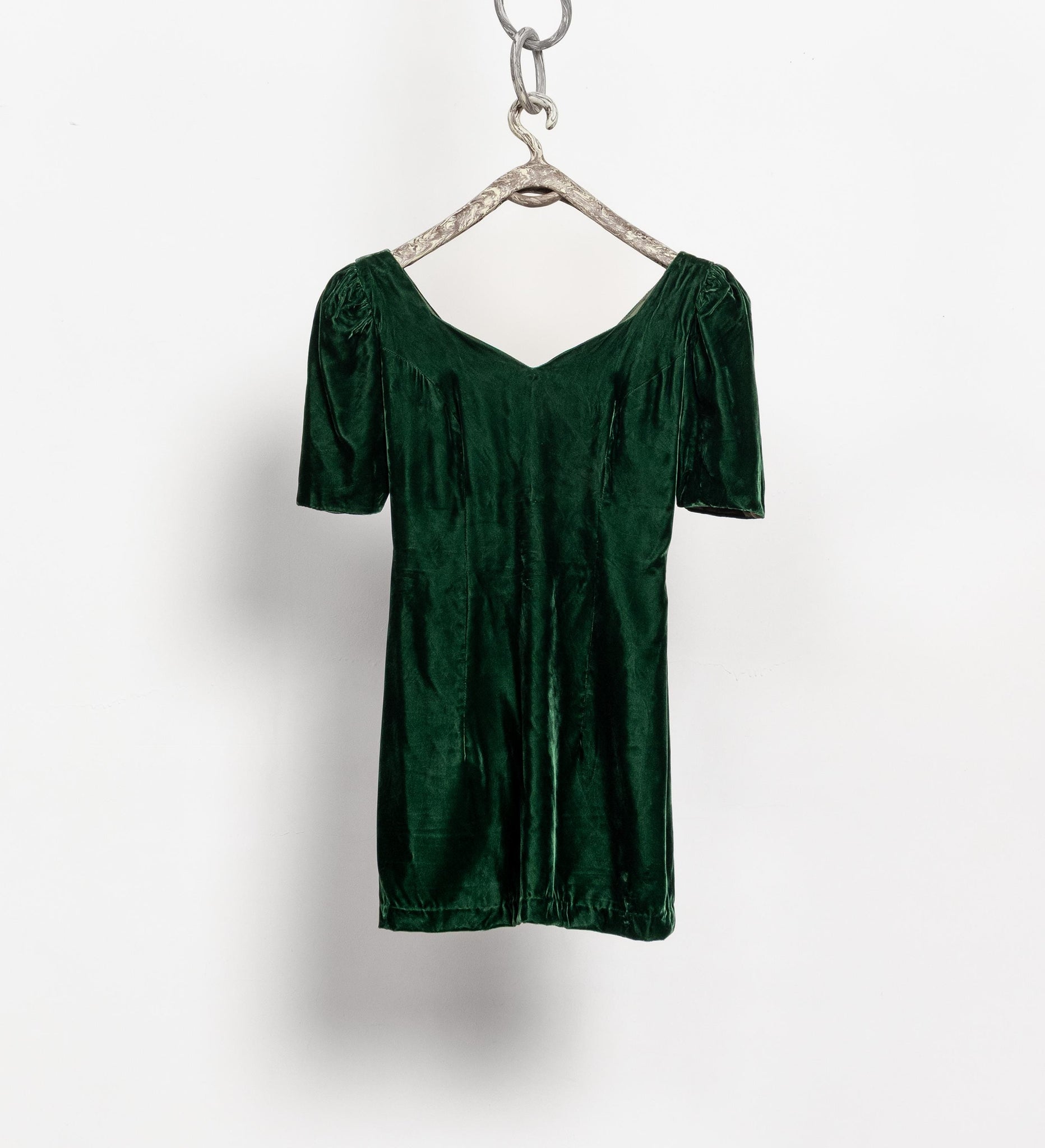 Green velvet dress on a hanger against a white background