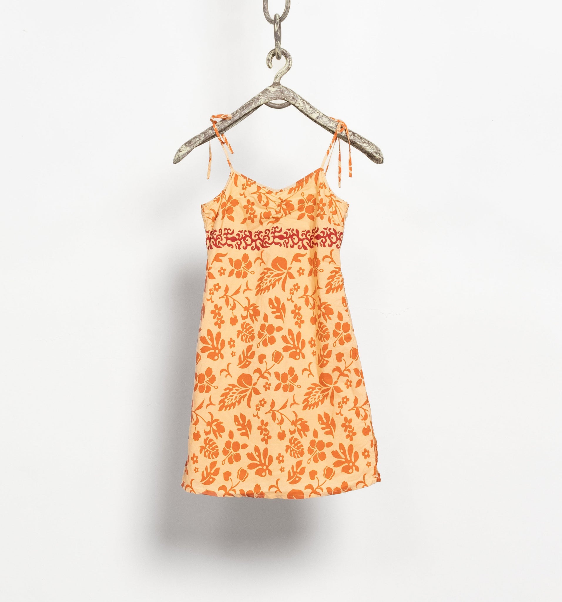 Orange floral dress on a hanger against a white background