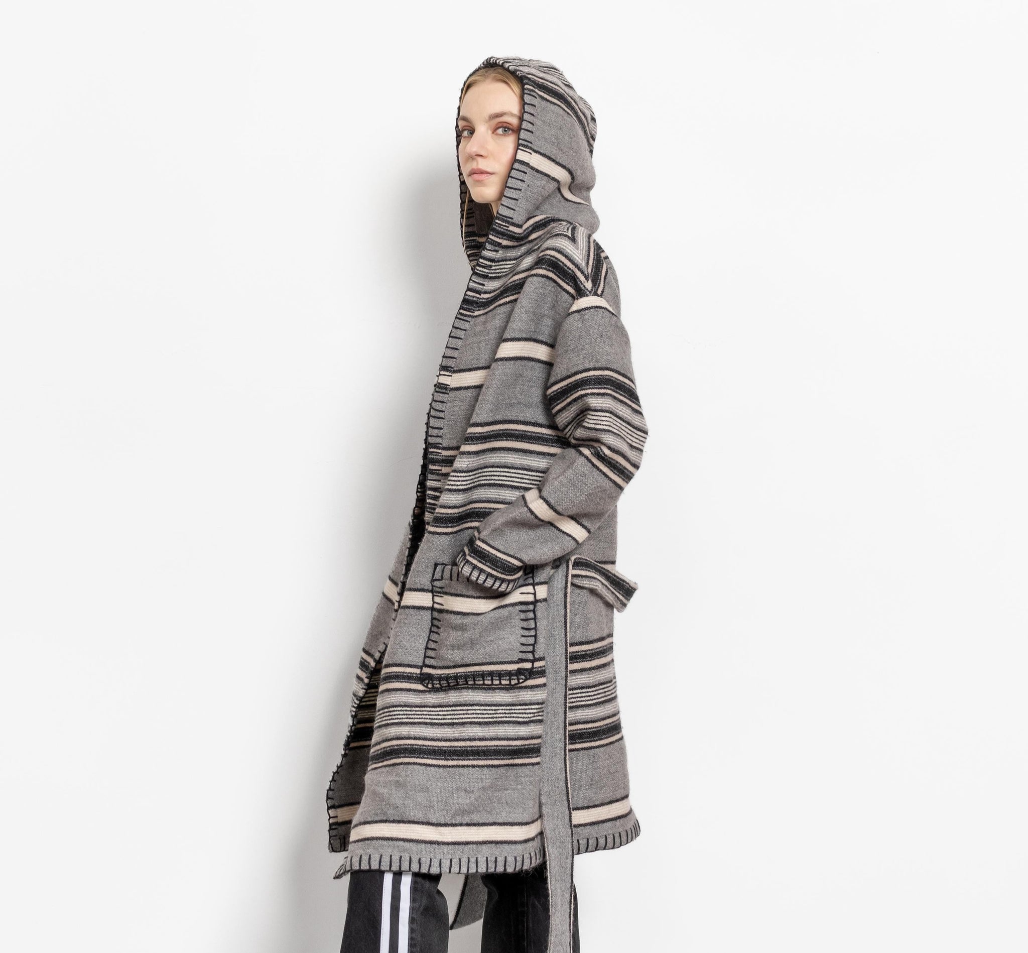 Person wearing a long, patterned coat with a hood on a white background