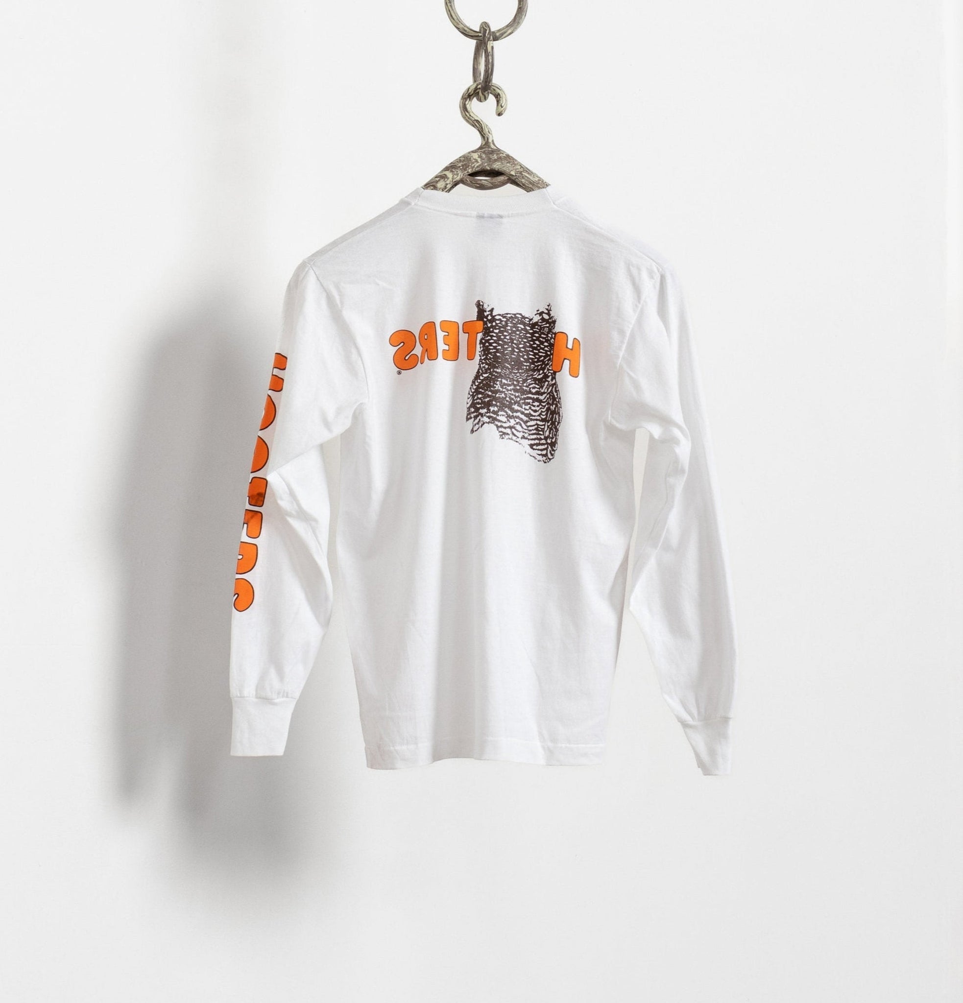 White long-sleeve shirt with graphic design on a hanger against a white background