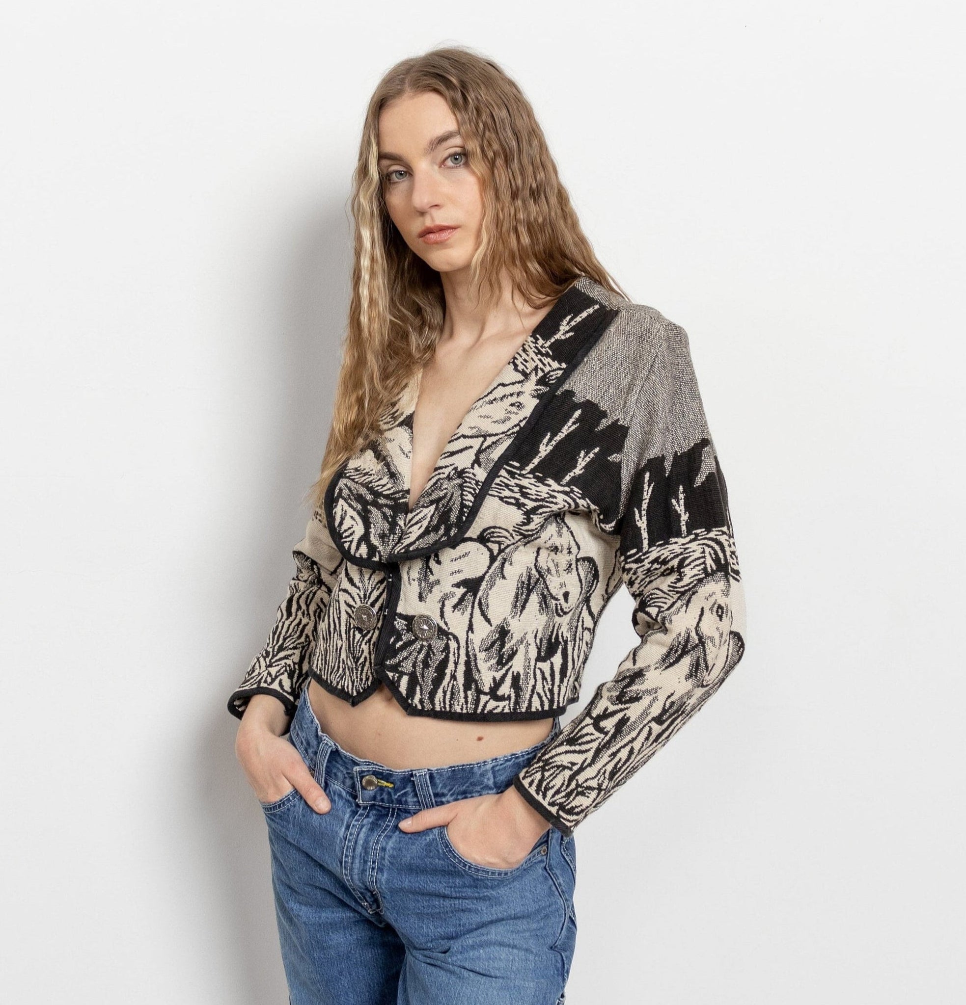 Woman wearing a patterned sweater and jeans on a plain background