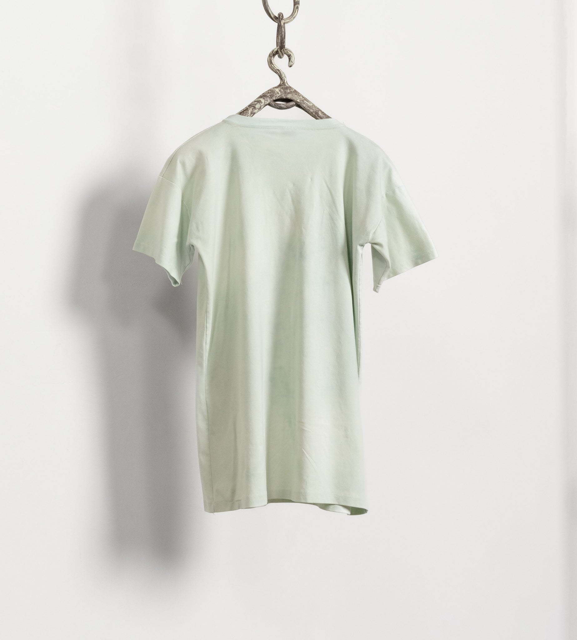 Light green t-shirt on a hanger against a white background