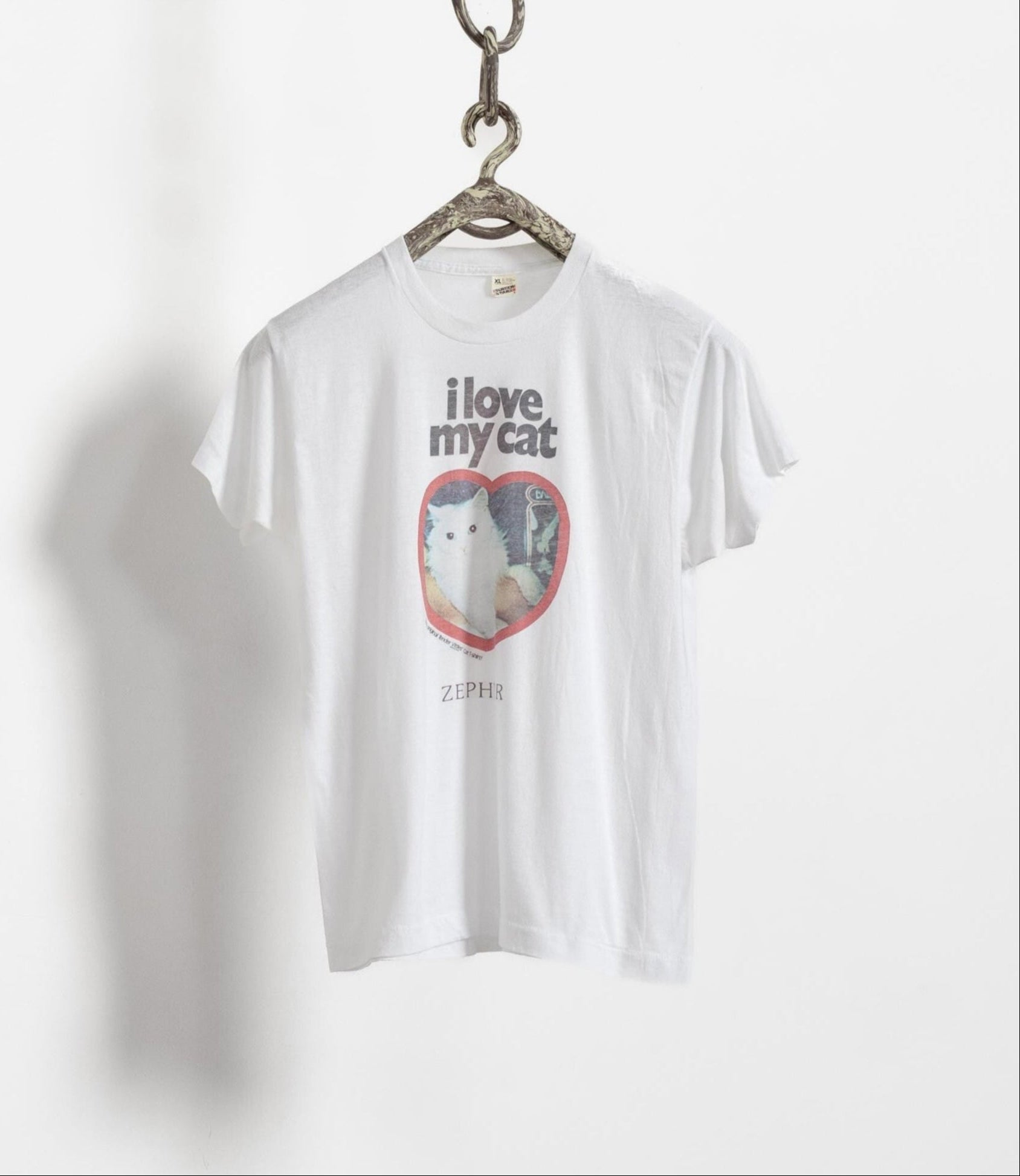 White t-shirt with the text 'I love my cat' and a heart shape, displayed on a hanger against a white background.