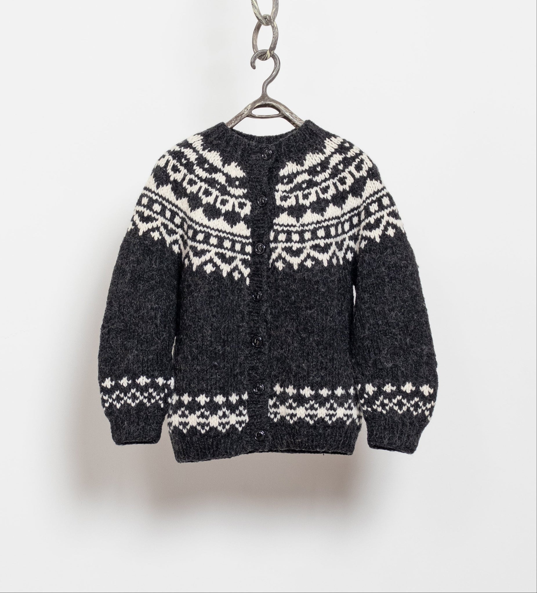 Black sweater with white patterns hanging on a white background