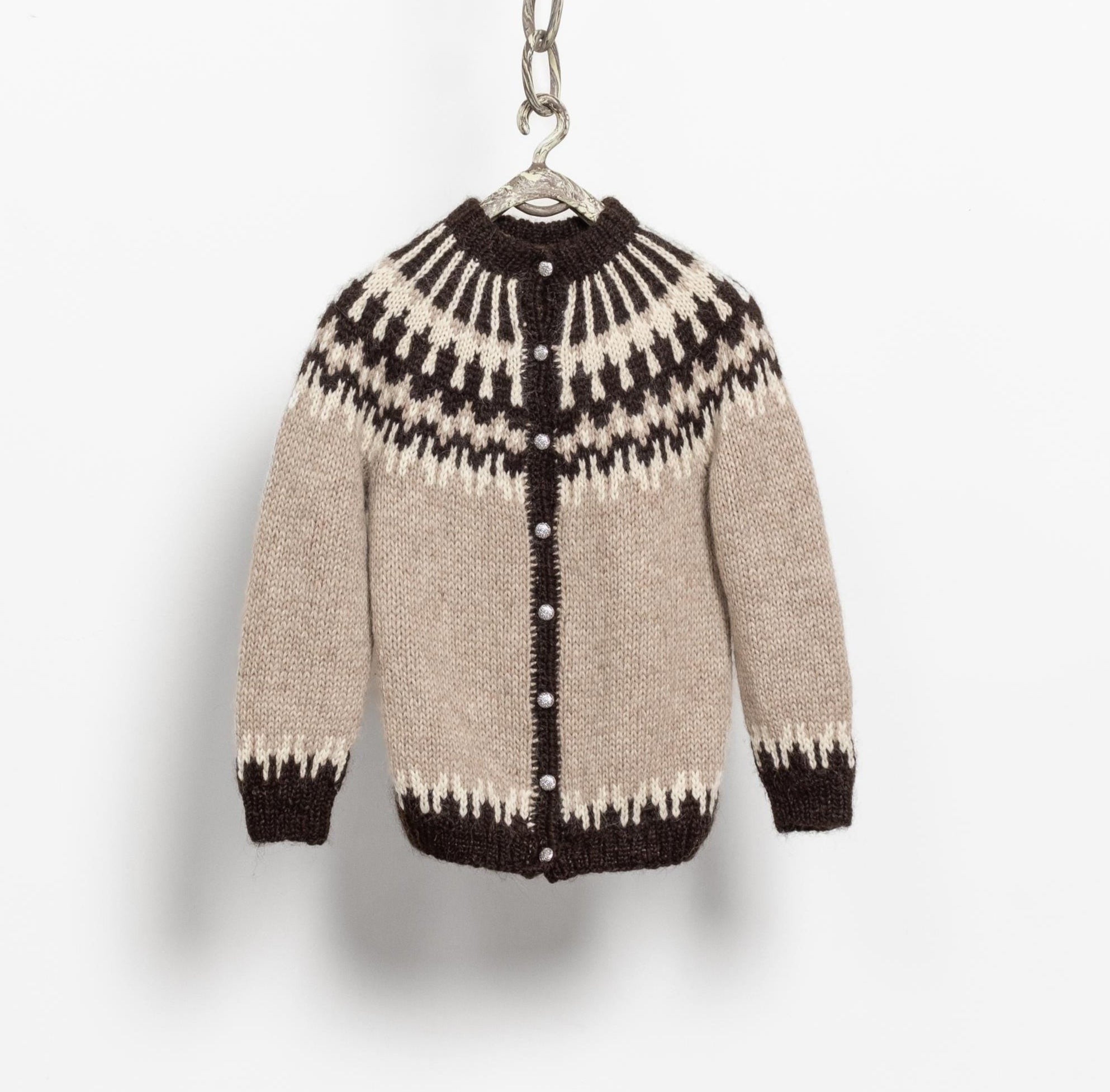 Miniature sweater with black and white pattern on a hanger against a light gray background